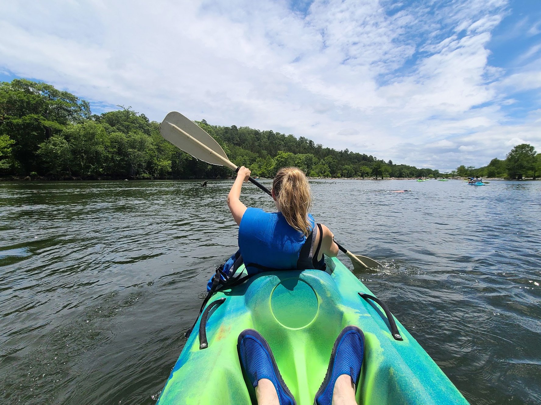 Lydia in the front of a tandem kayak on the Mountain Fork River.