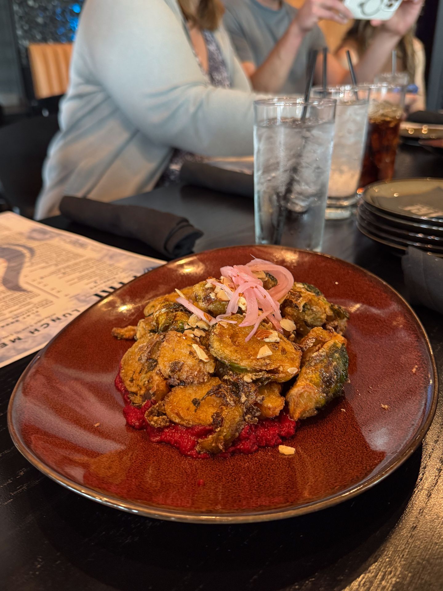 A brussel sprouts appetizer topped with onions and served on a bed of beet hummus from Fyre Modern Grill