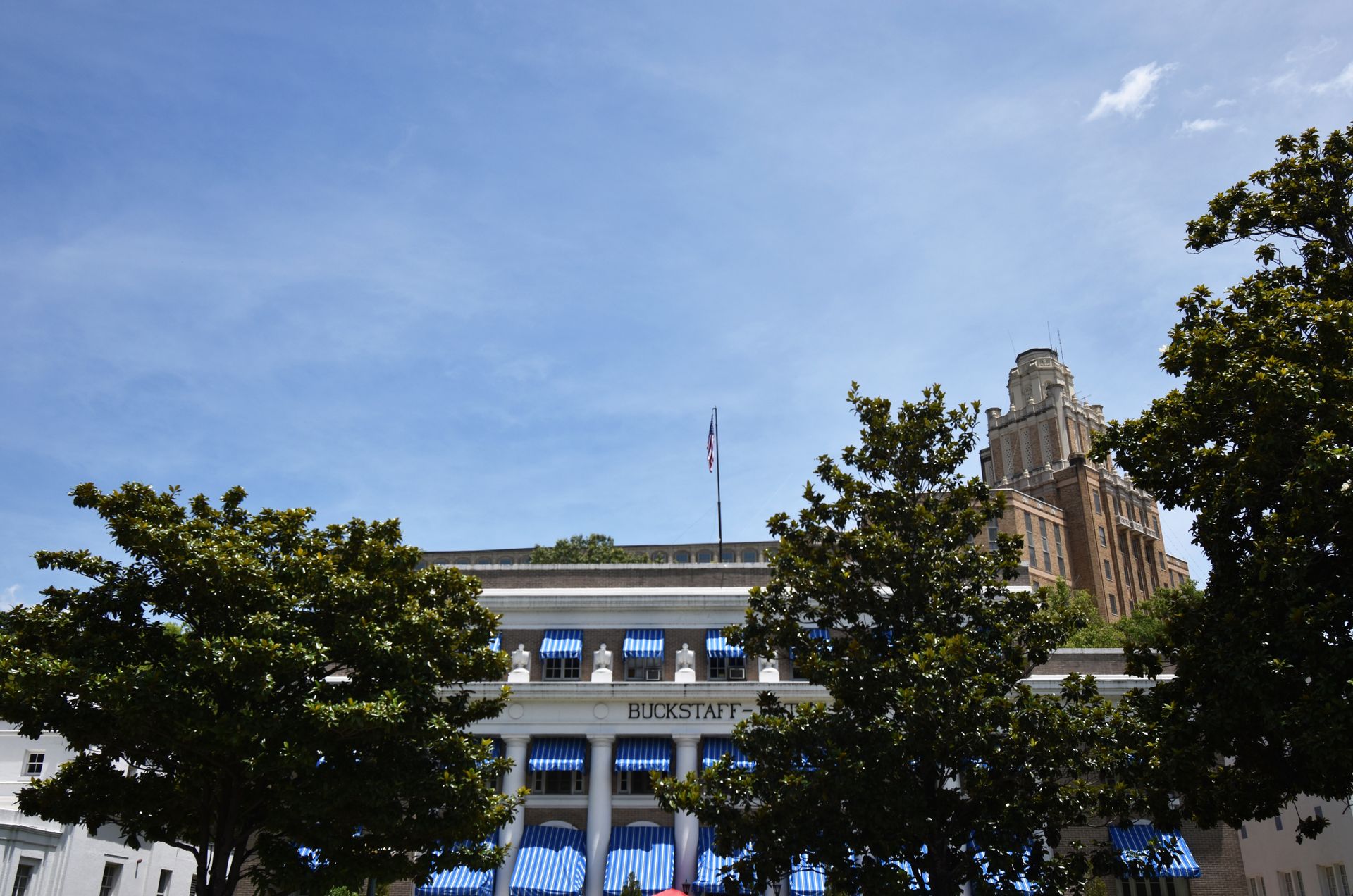 A exterior of Buckstaff Bathhouse. There are some trees in front and awnings with blue and white stripes.