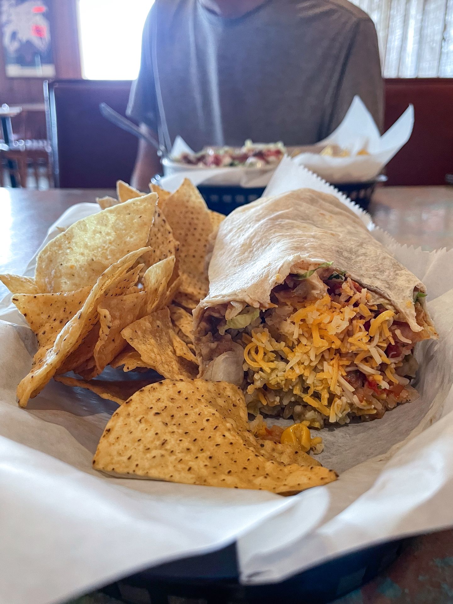 A burrito with chips sitting on a table at Bravo Burrito