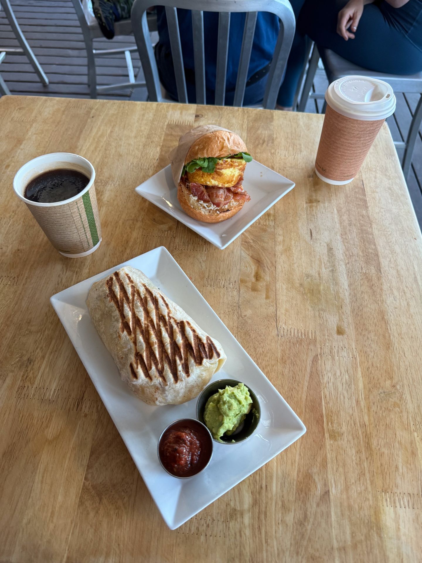 One plate with a burrito, and another plate with a breakfast sandwich from Hanalei Bread Company