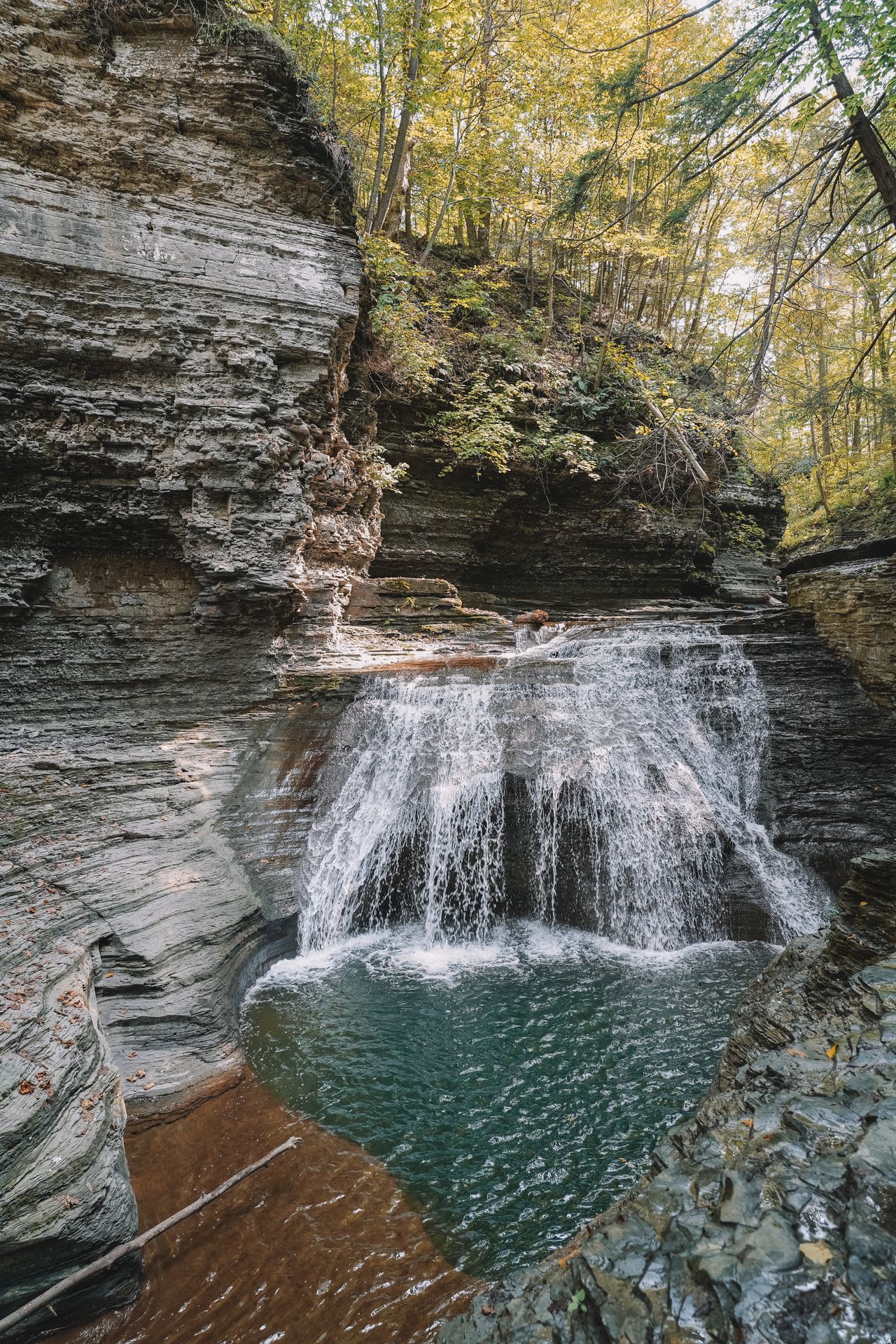 A small waterfall falling into a pool of bright, blue water at Buttermilk Falls.