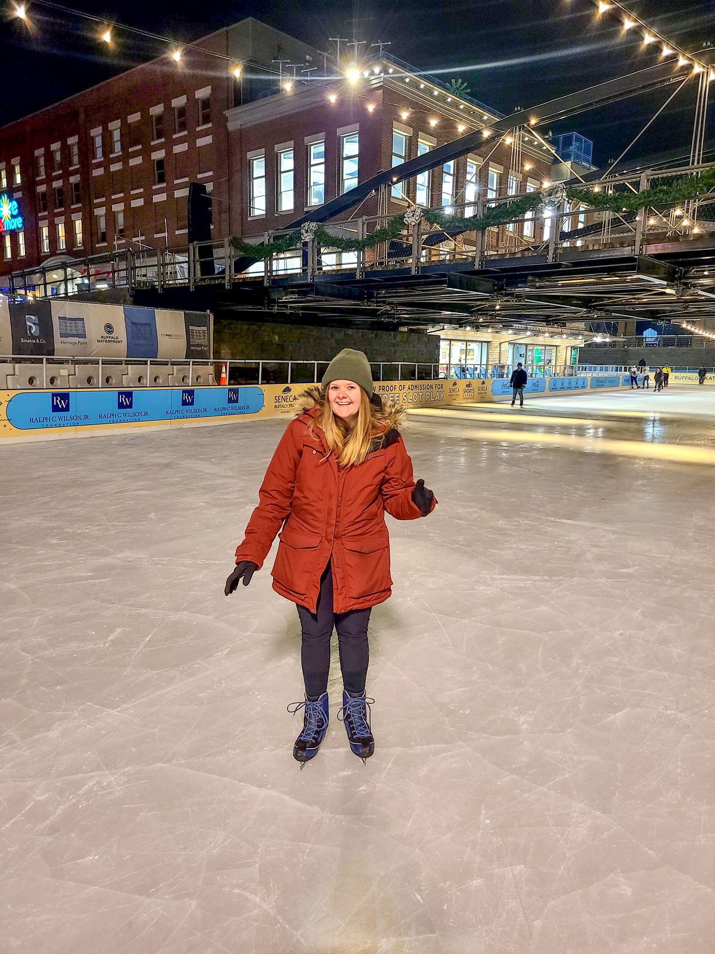 Lydia ice skating wearing a red coat and green hat.