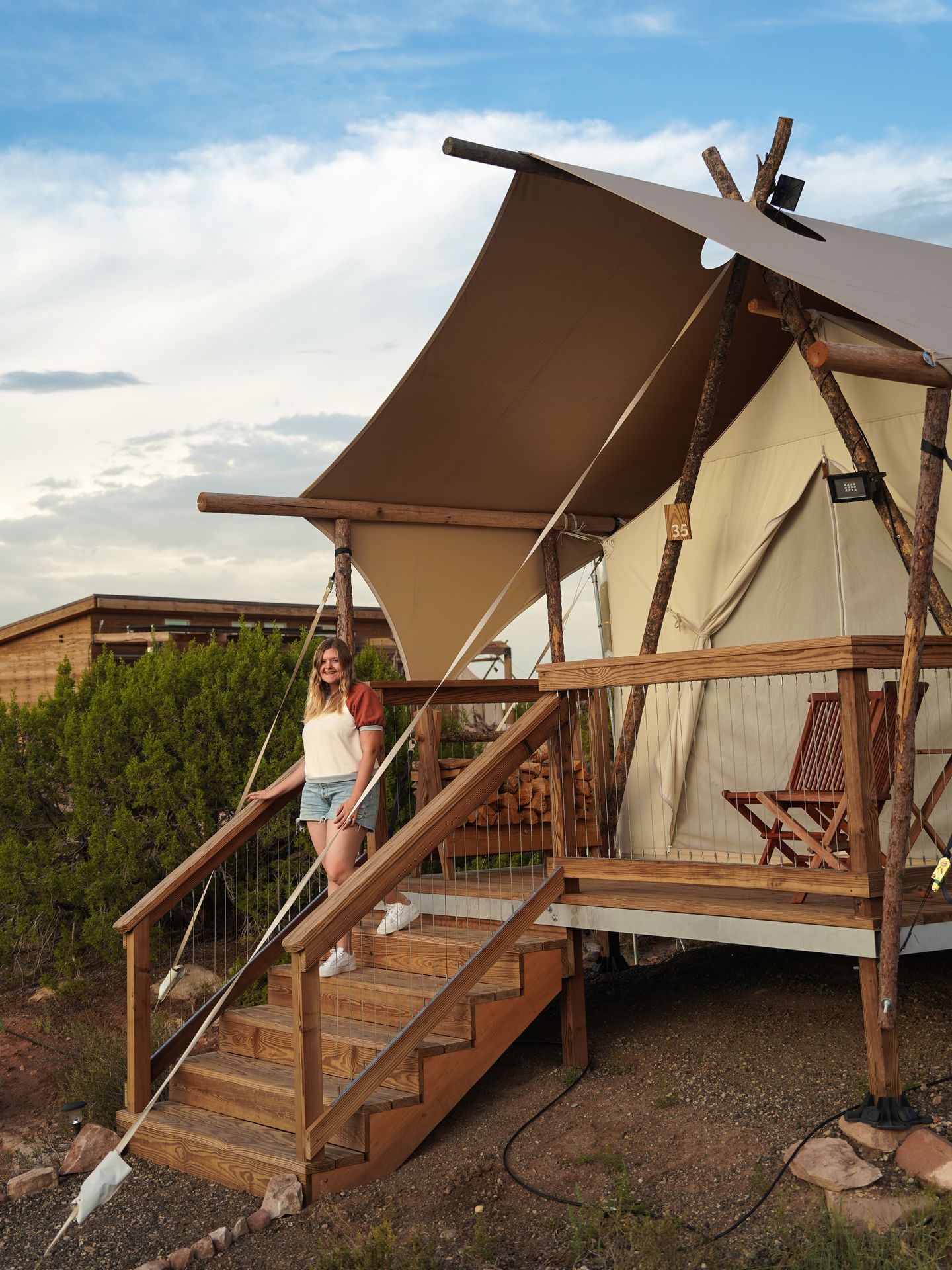 Lydia standing on the steps leading up to a tent at Under Canvas Moab