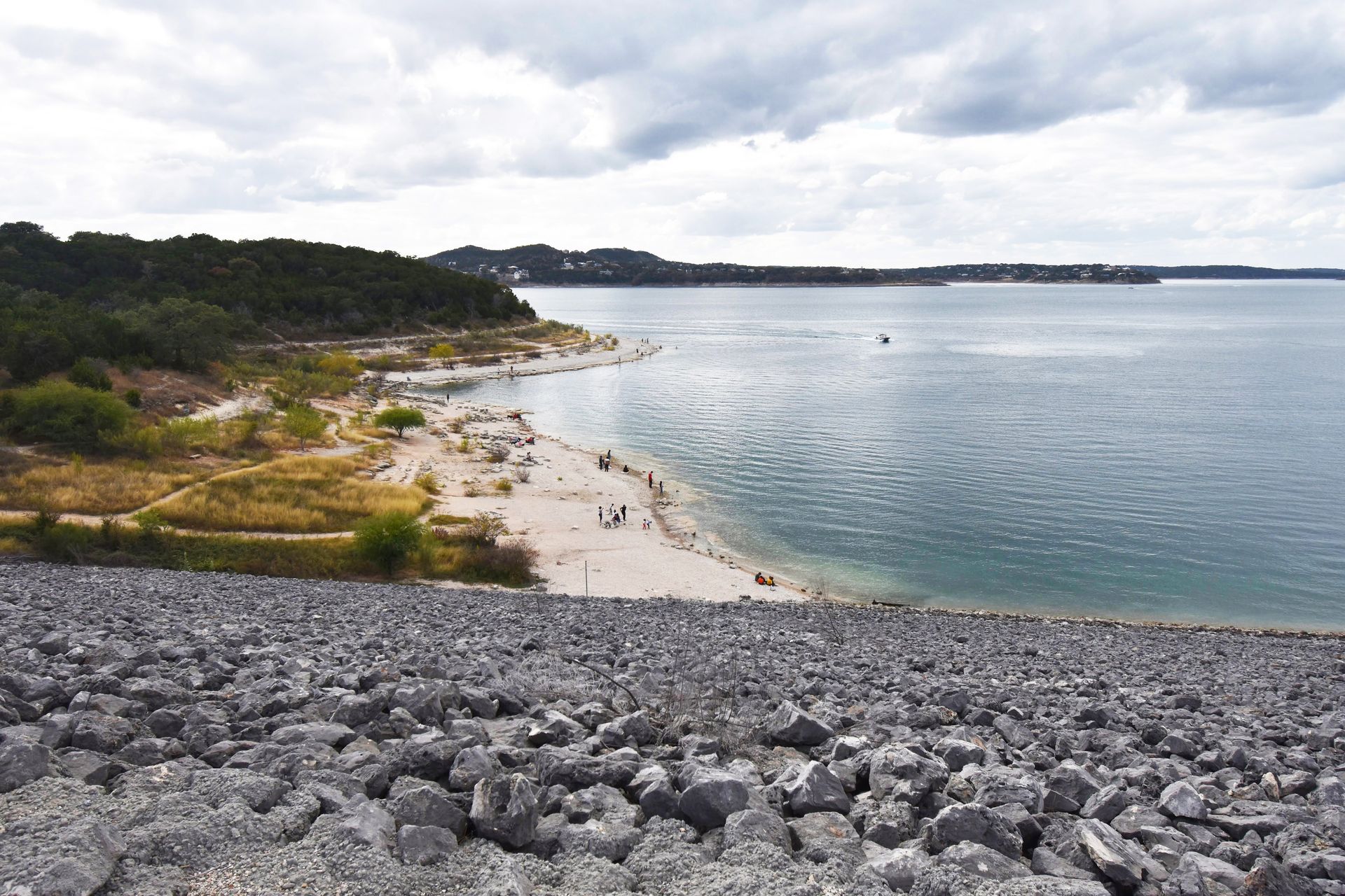 Looking down from a dam at Canyon Lake. A beach sits on the banks of the water.