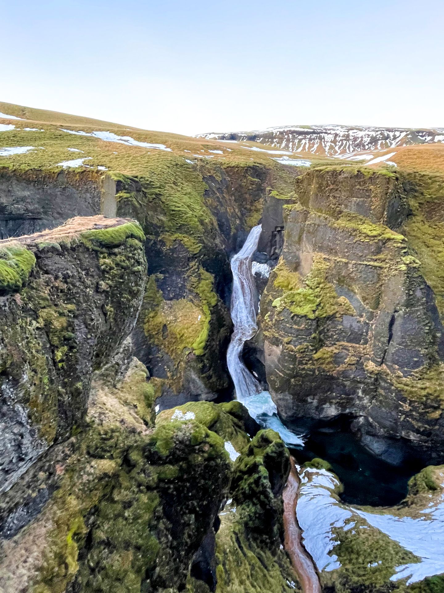 A waterfall cascading down a canyon. The canyon is covered in bright greenery