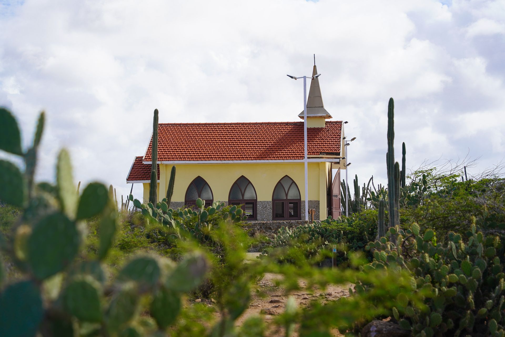 A small, yellow church with cacti in the foreground