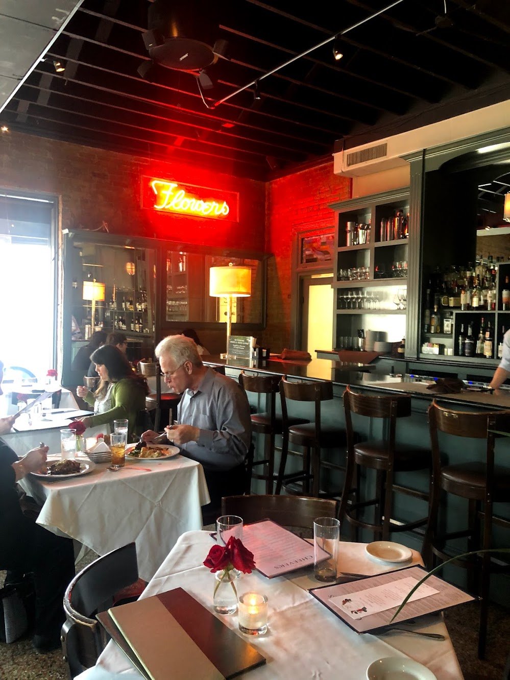 The inteior of Cheever's Cafe. There is a red neon side next to the bar.