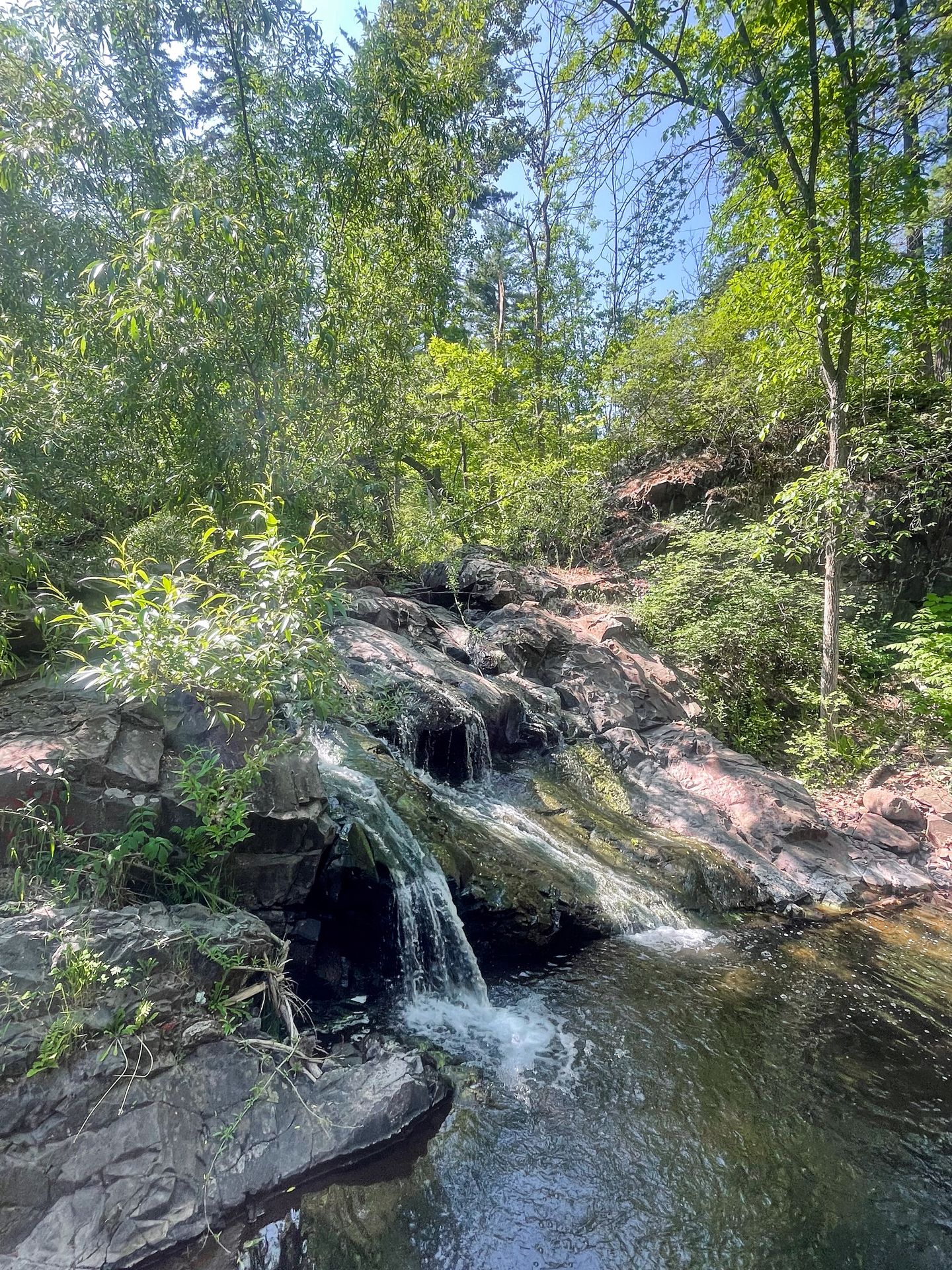 A series of small waterfalls flowing down some rocks and into a pool of water.