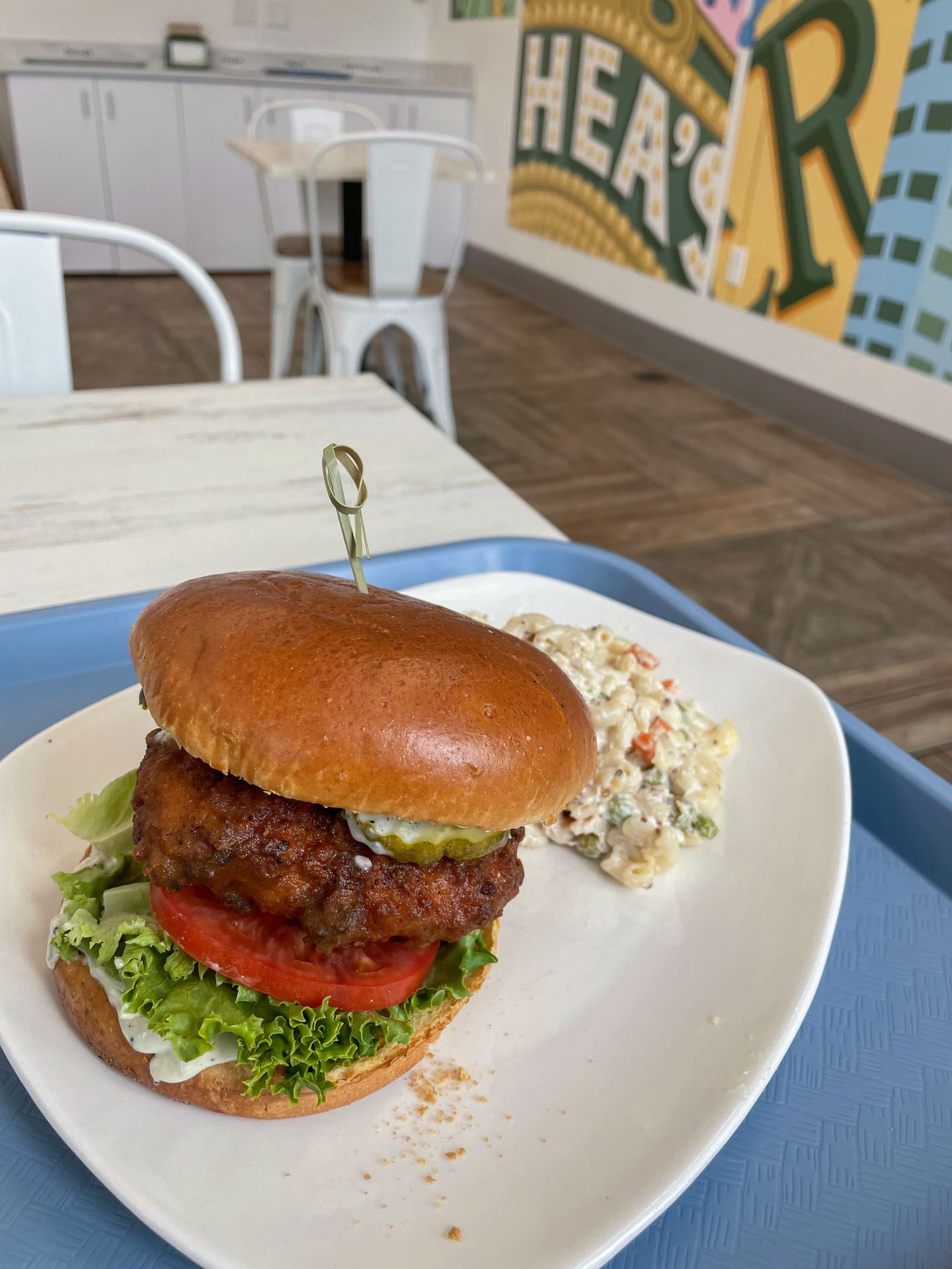 A vegan buffalo chicken sandwich served with macaroni.