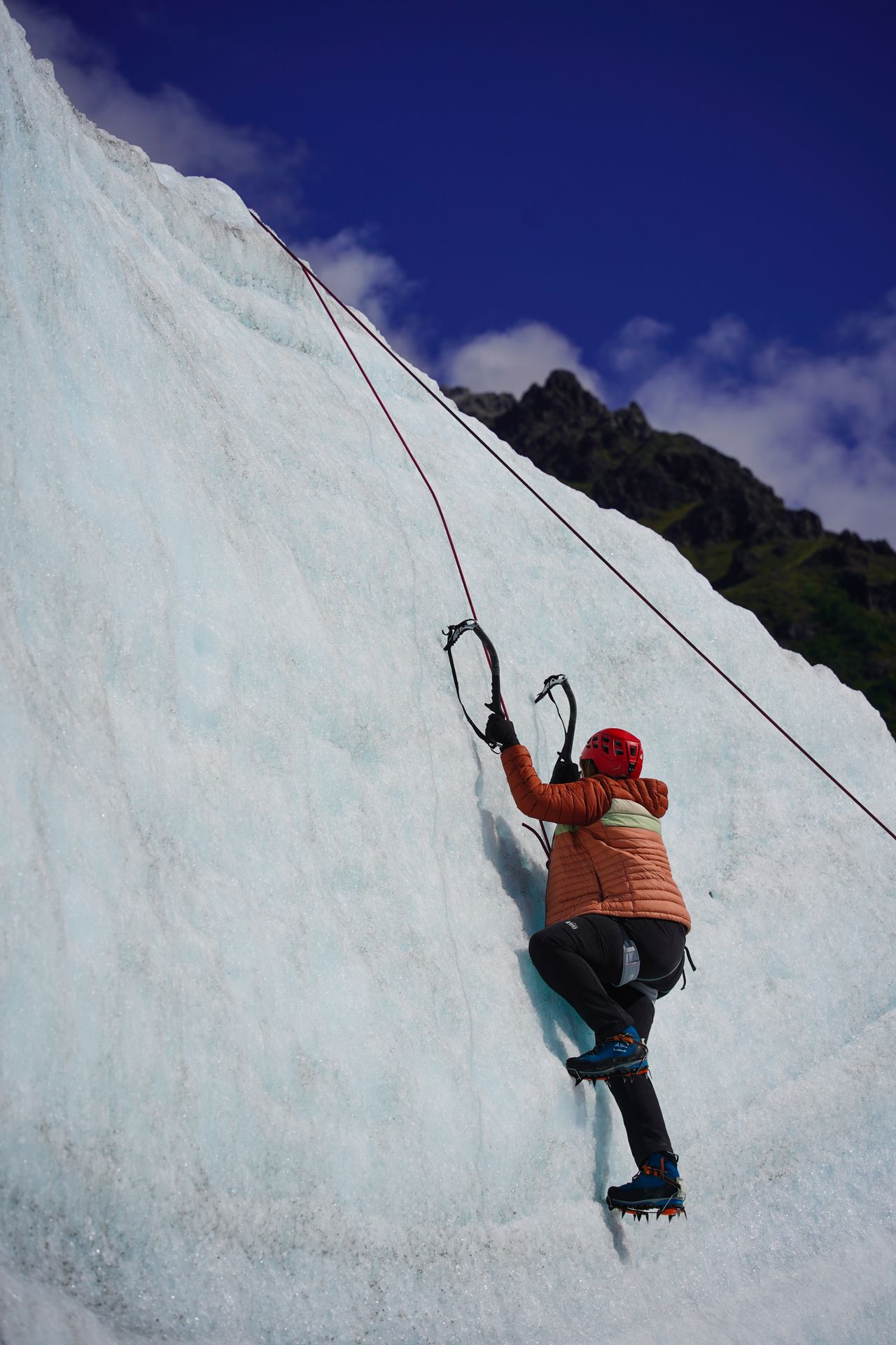 Lydia on a sheer icy cliff while ice climbing on the Root Glacier