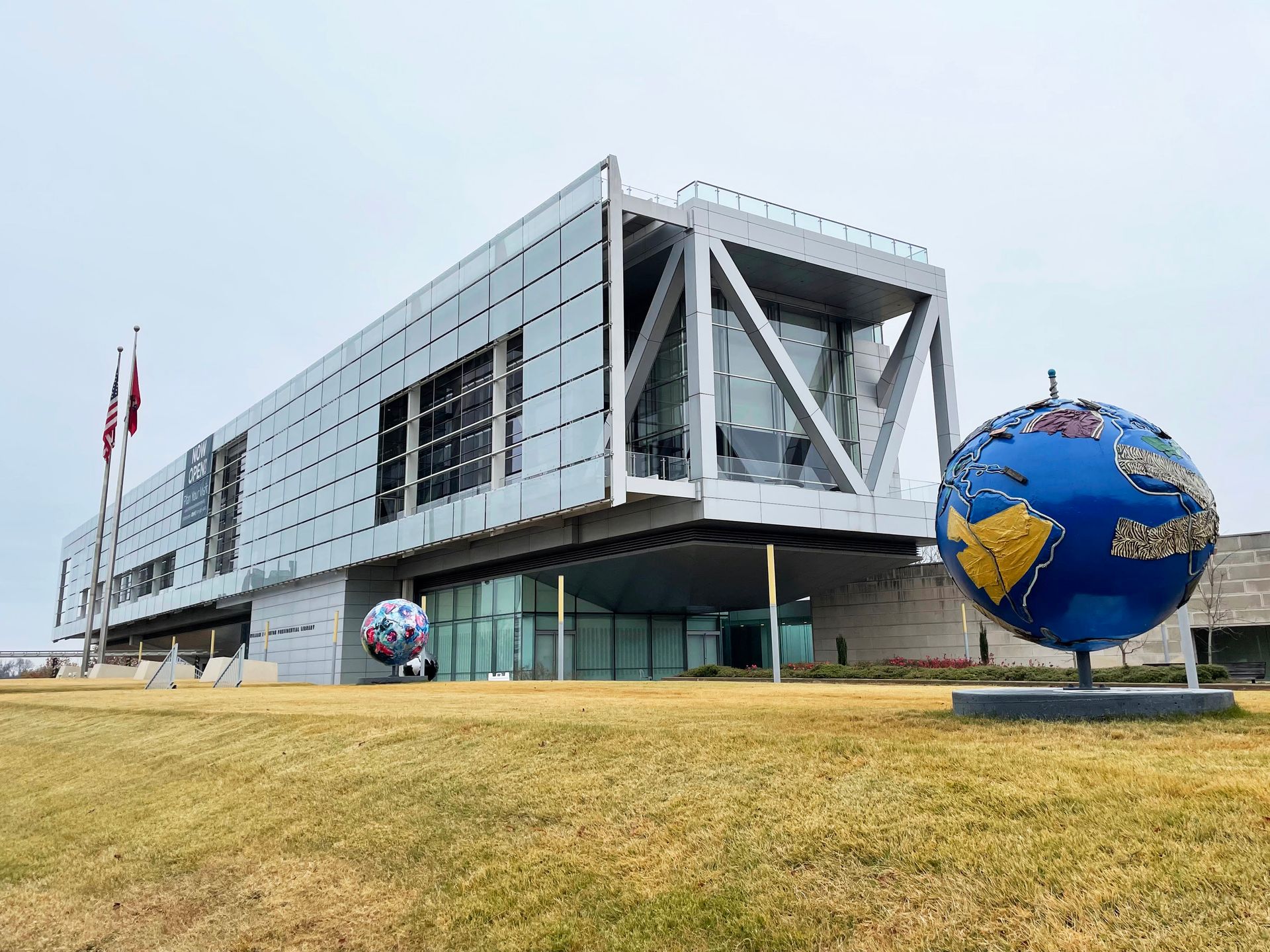 A view of the outside of the Clinton Museum and Library. The building is long and rectangular and an earth sculpture sits in front.