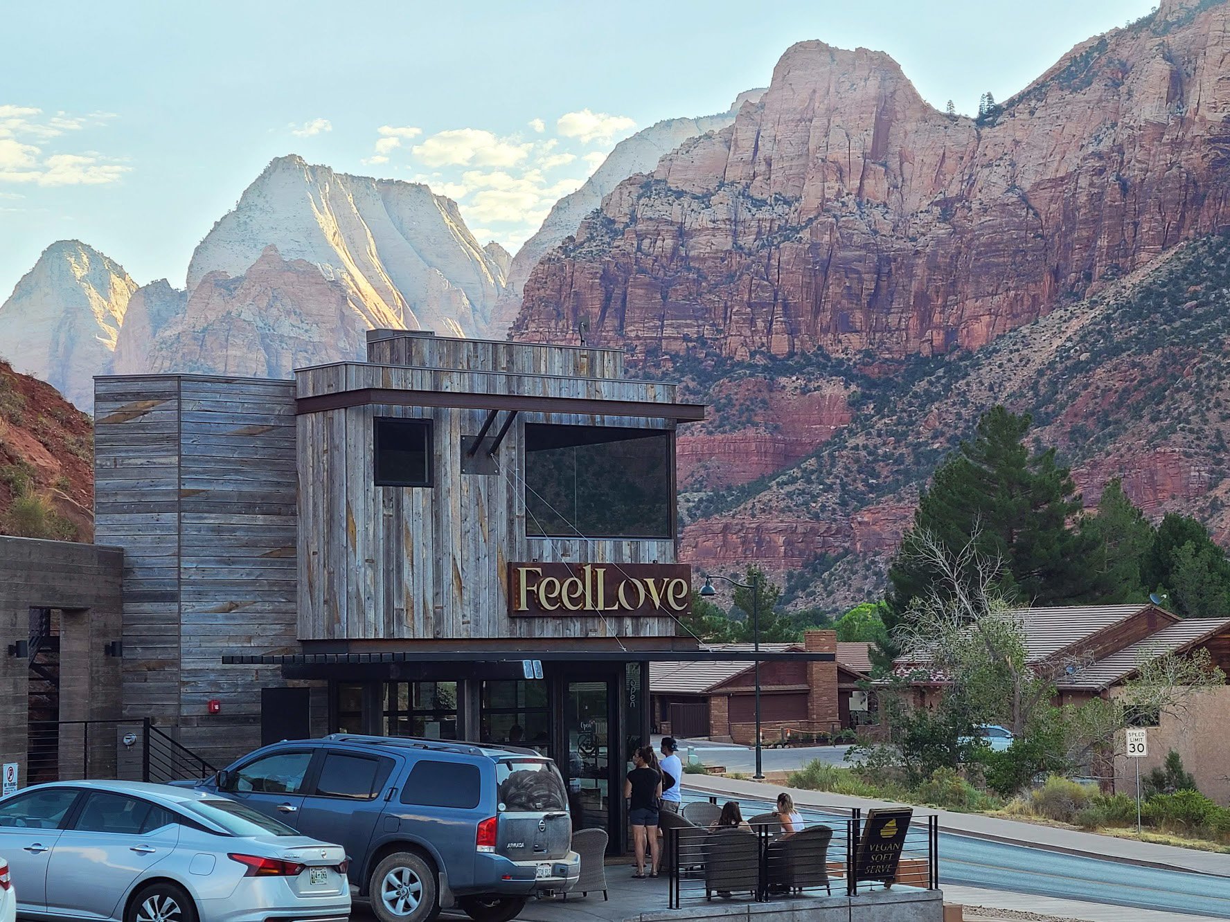 A rustic coffee shop that reads "Feel Love" with the orange cliffs of Zion in the background.