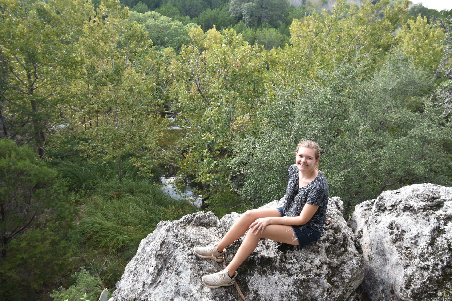 Lydia sitting on a rock on a trail in Colorado Bend State Park.