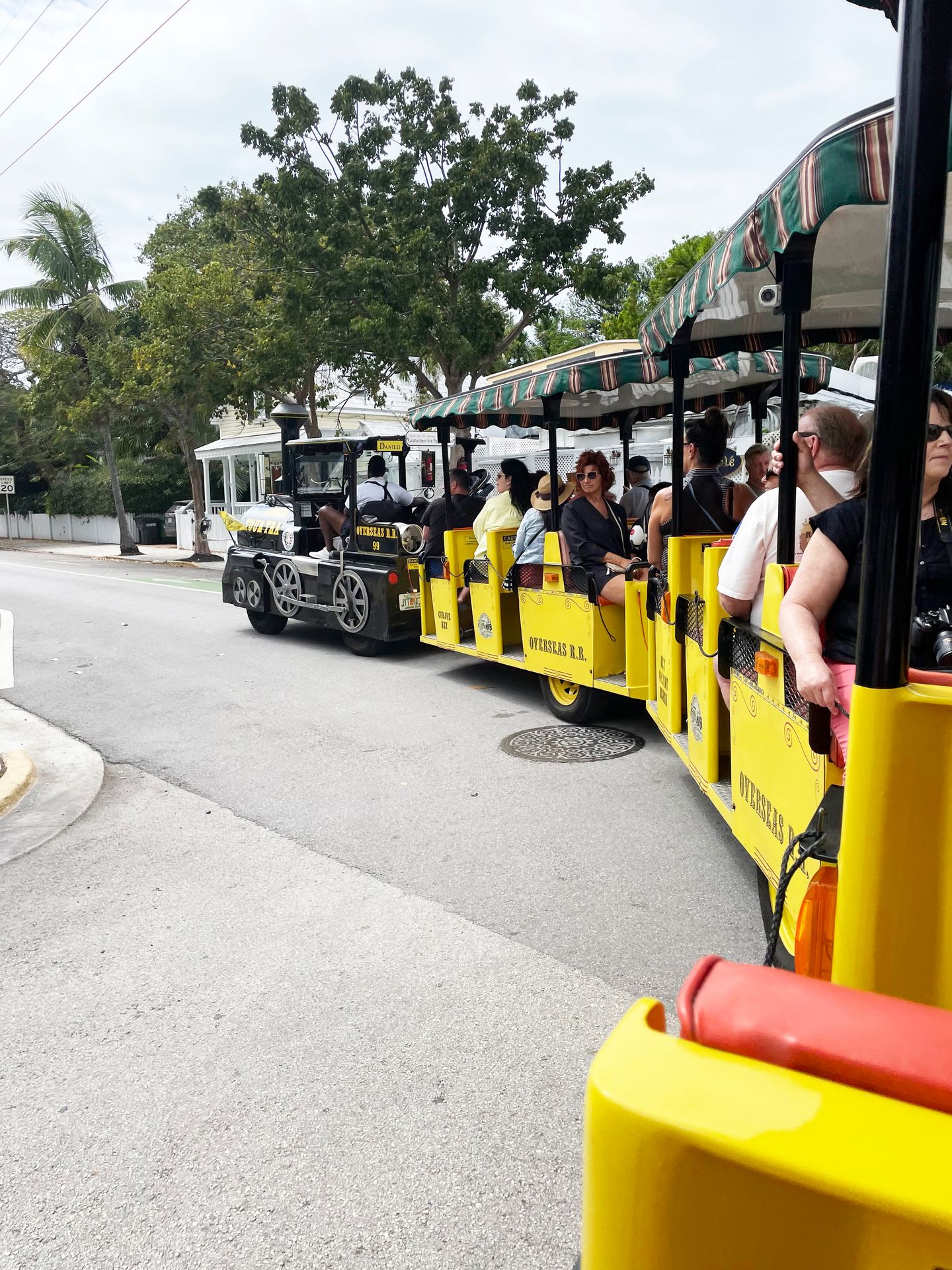 A side view of a yellow, open air train that is turning left