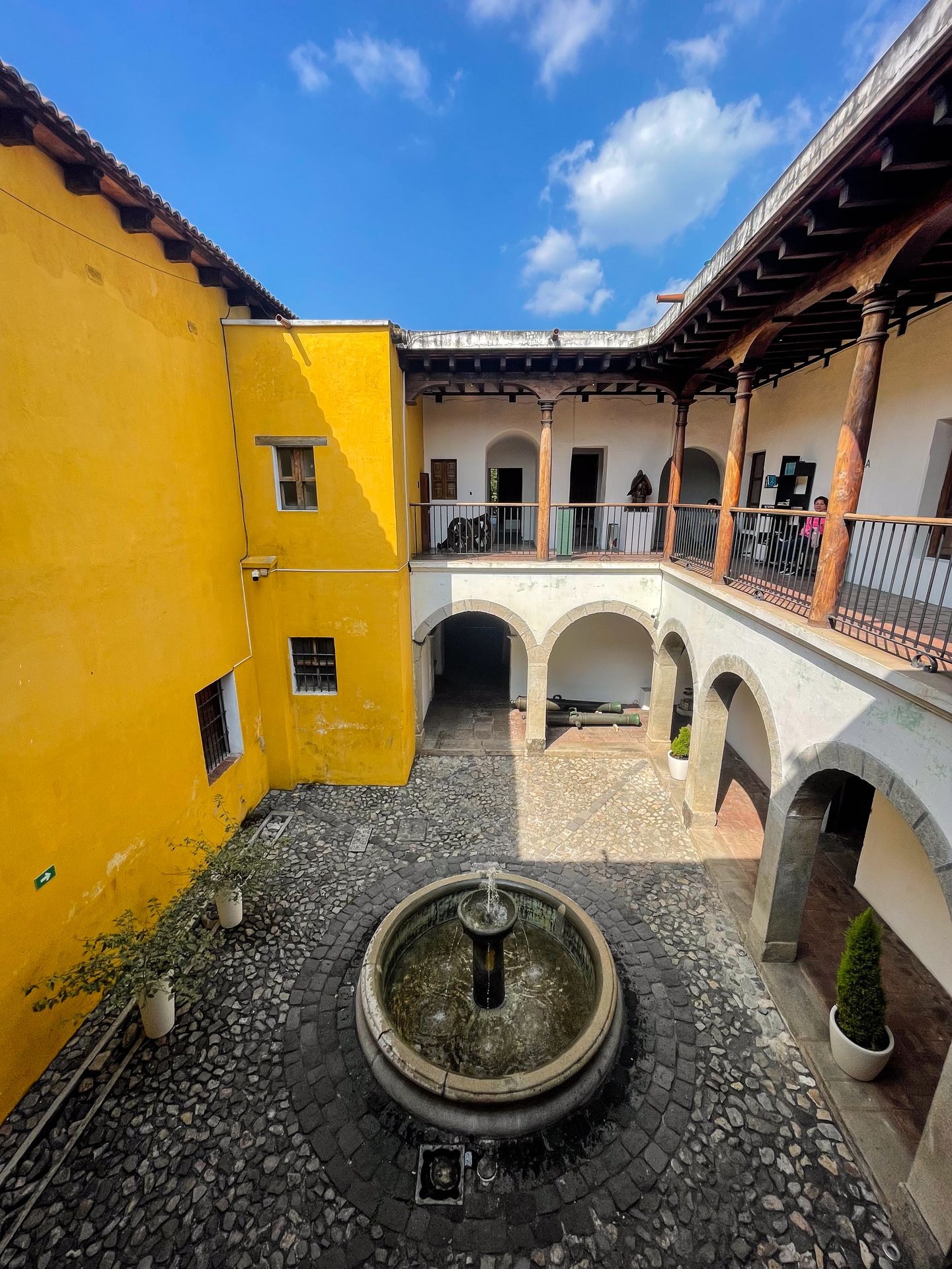 The courtyard at the Museo Nacional de Arte de Guatemala, which has a fountain in the middle and a yellow wall
