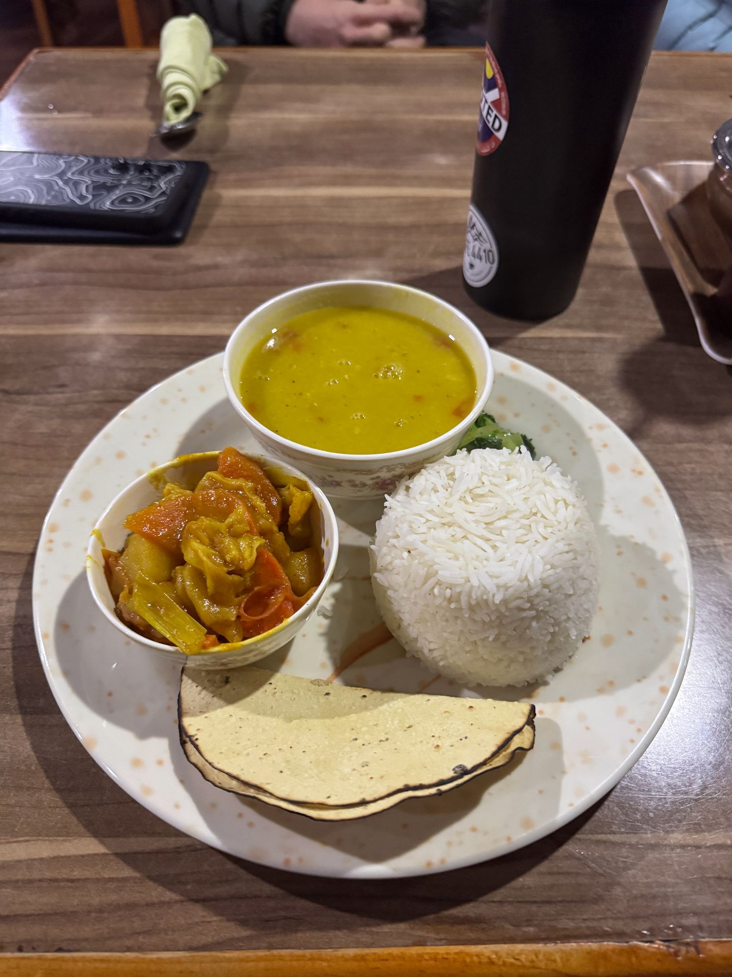 A plate with soup, rice, tortillas and vegtables