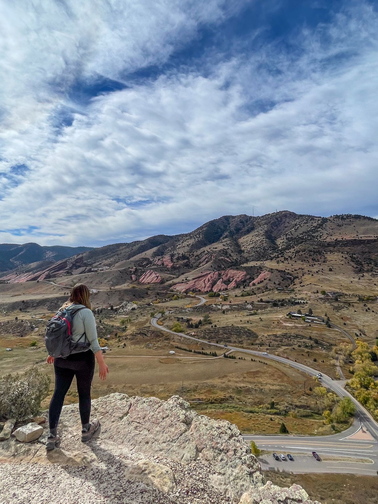 Lydia standing on a rock and looking out red rocks from Dinosaur Ridge