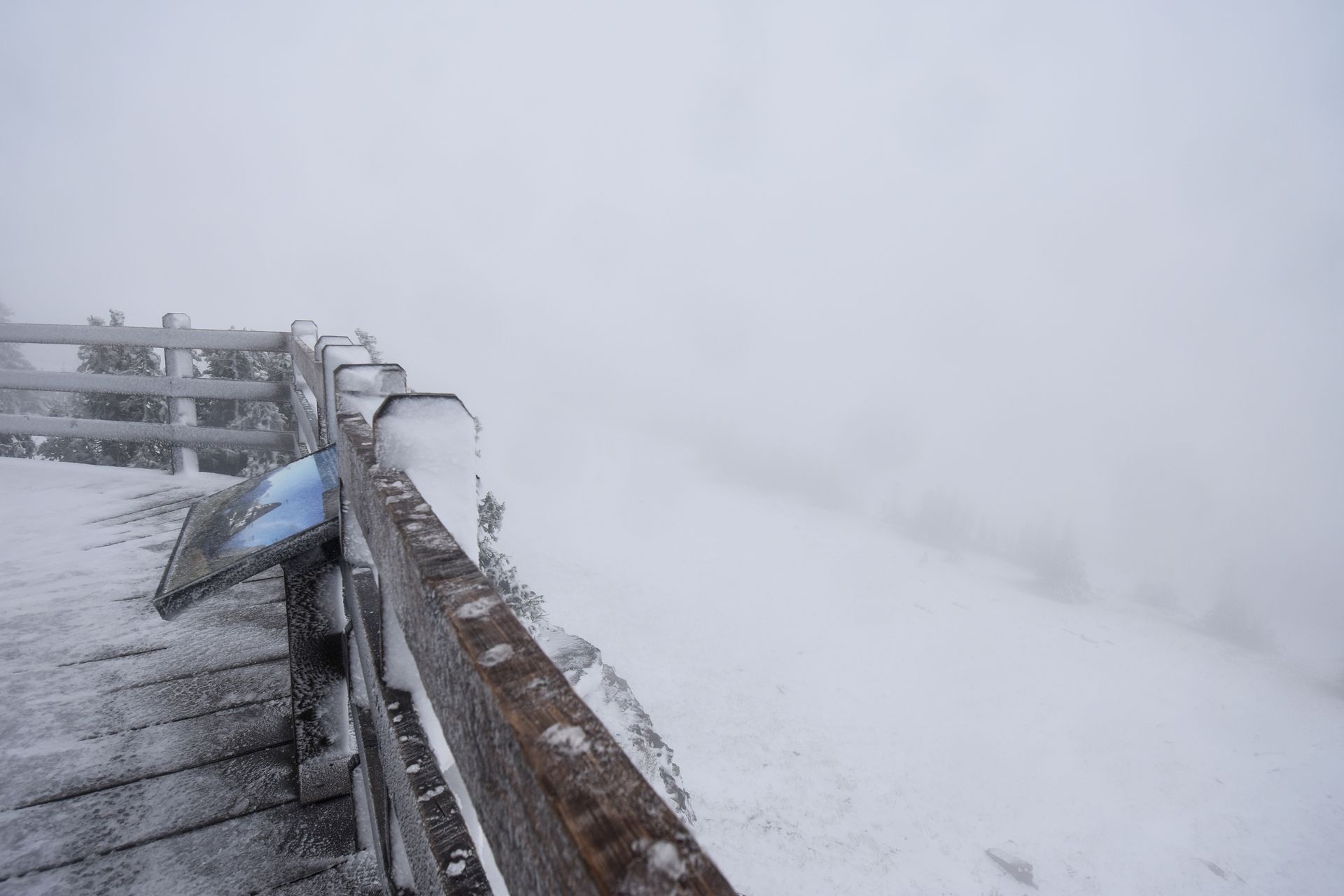 A wooden fence with a view that is completely covered in fog.