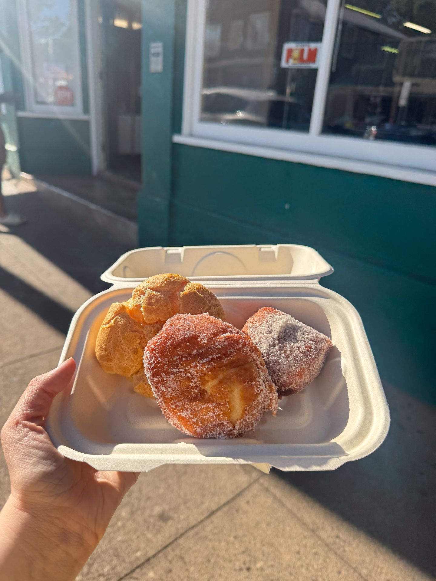 A container with 2 donuts and a cream puff from Komoda Bakery