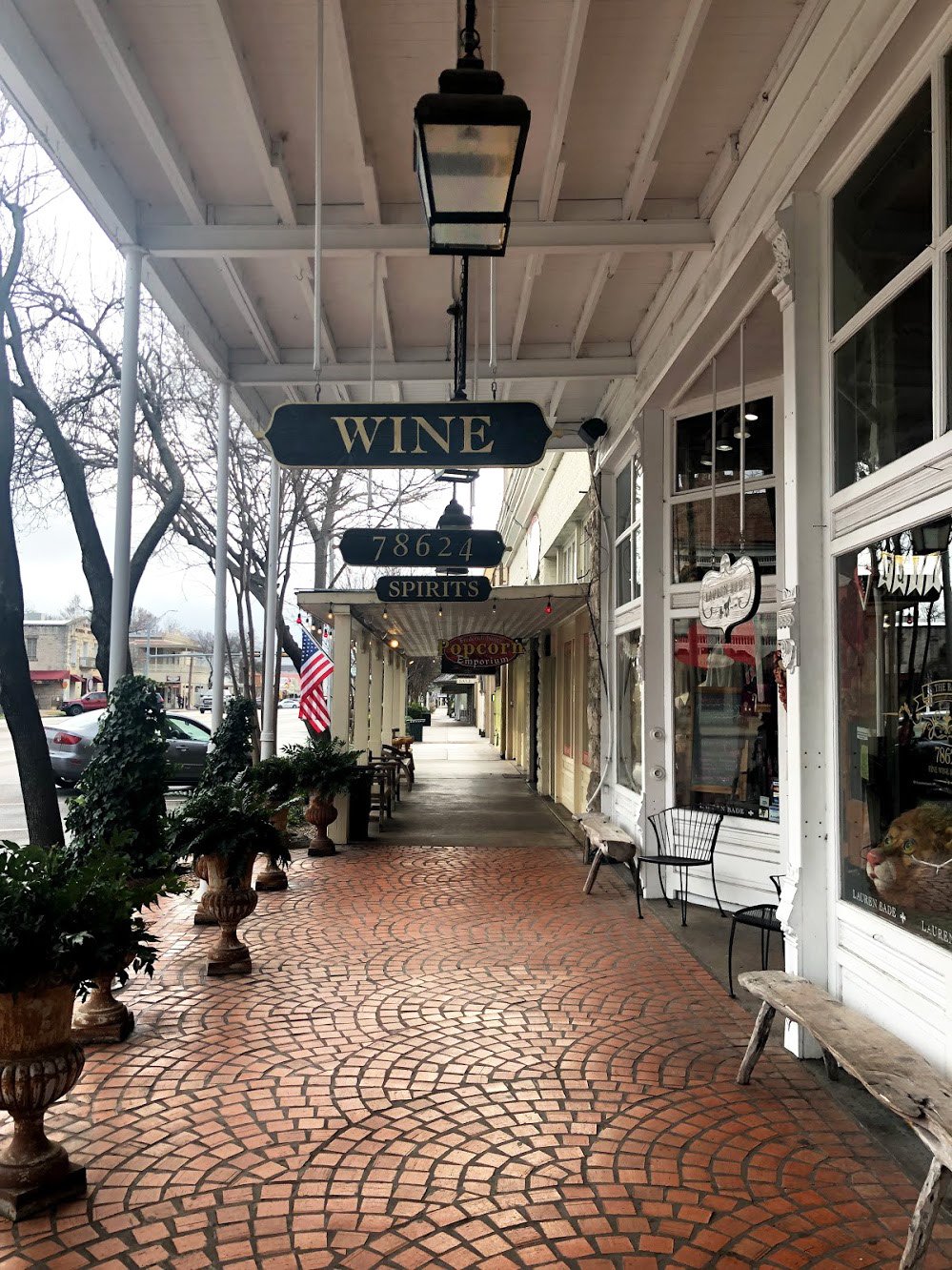 A street in downtown Fredericksburg. Wooden signs for Wine and Spirits hang from above.