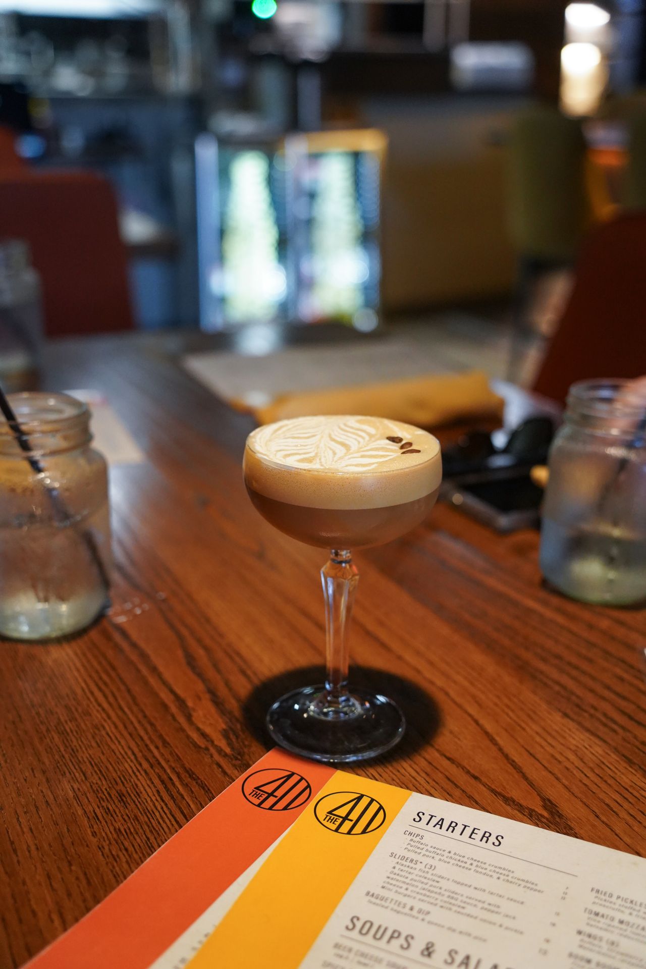 An espresso martini cocktail next to menus at 411 Restaurant and Lounge