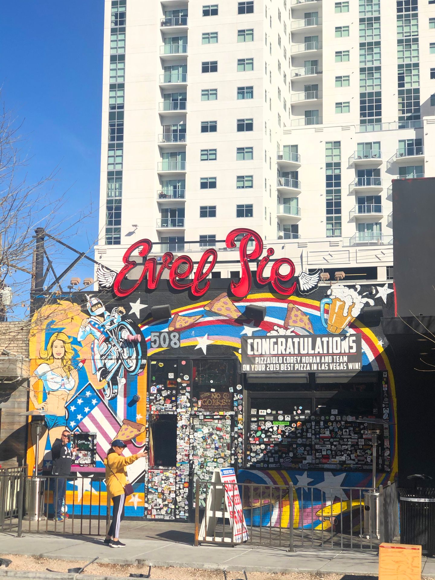 The exterior of Evel Pie Pizza. The building is very colorful with artwork that includes a rainbow, a motorcyle, pizza, beer and an American flag