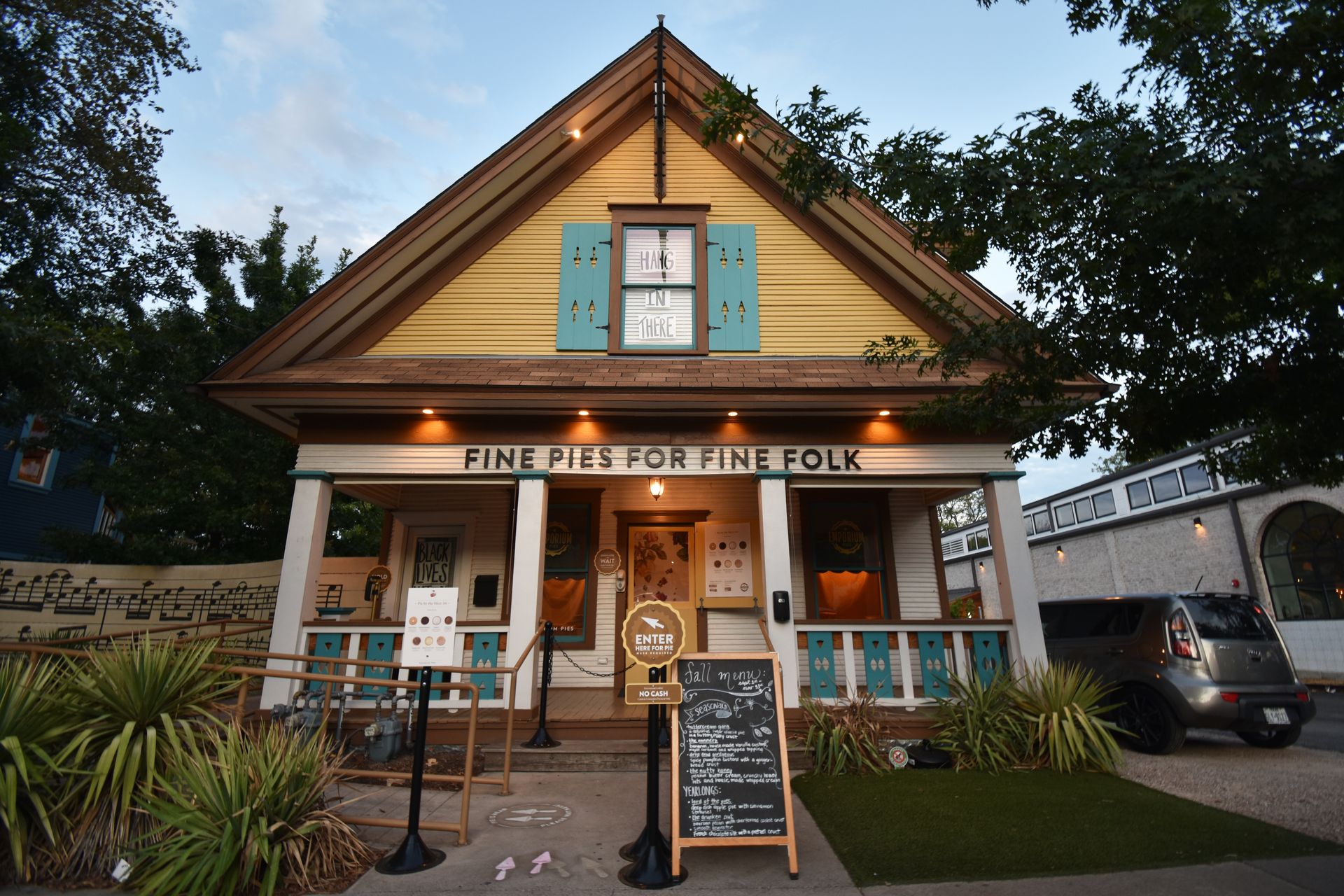 The exterior of Emporium Pies in Bishop Arts. The pie shop looks like a house painted white, yellow and blue.