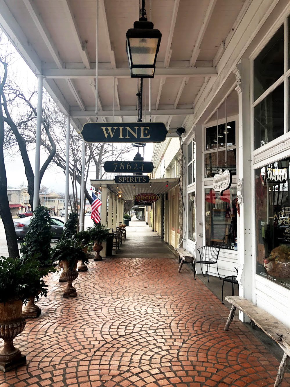 The side of downtown Fredericksburg. There are cobblestones on the ground and white buildings. A sign above reads "wine"