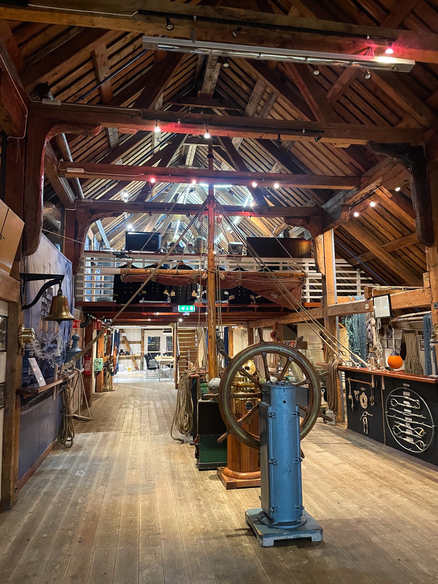 A room with a ship steering wheel and other sailing items in the Full Steam Museum.