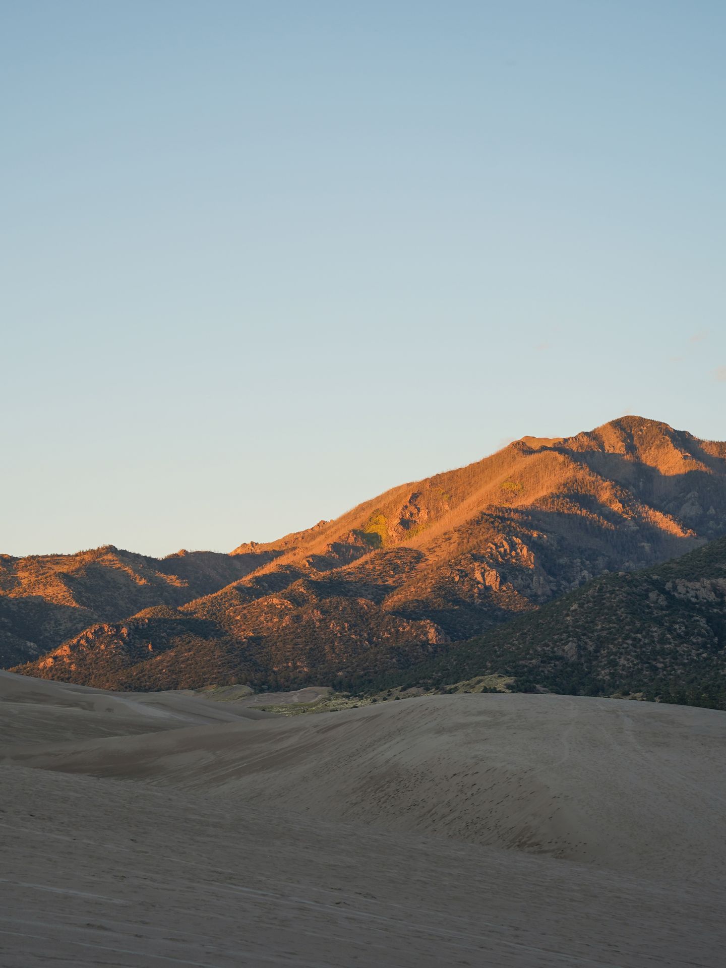 Mountains over sand dunes glowing at sunset