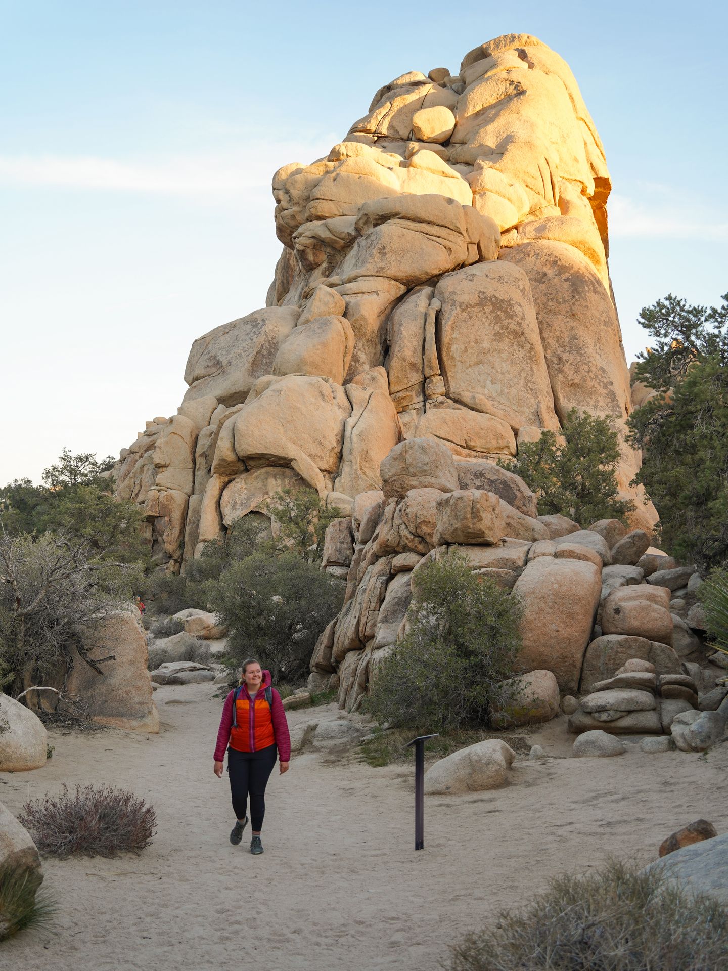 Lydia hiking next to a large, tan pile of boulders.