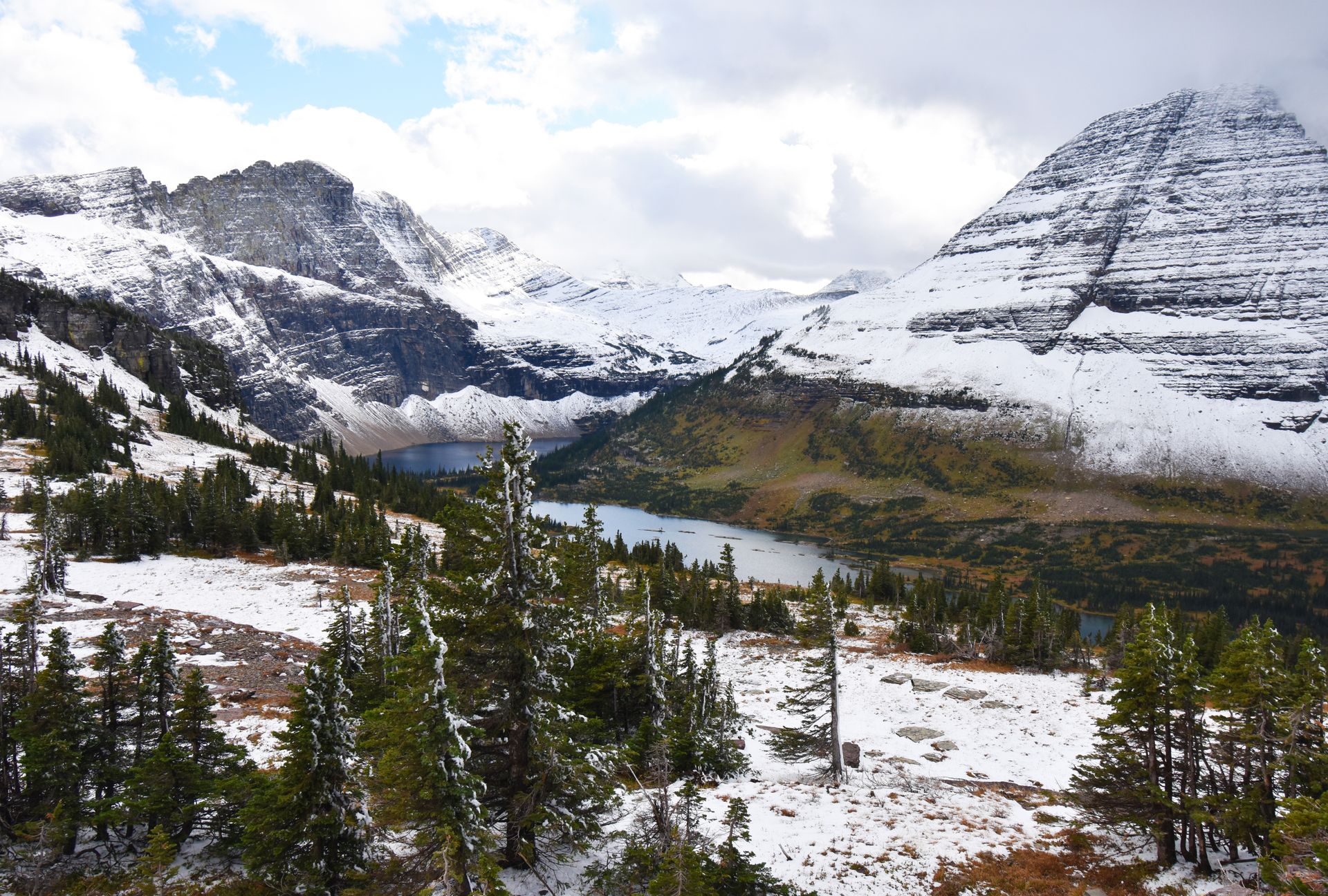 Looking at Hidden Lake, with the surrounidng mountains partially covered in snow.