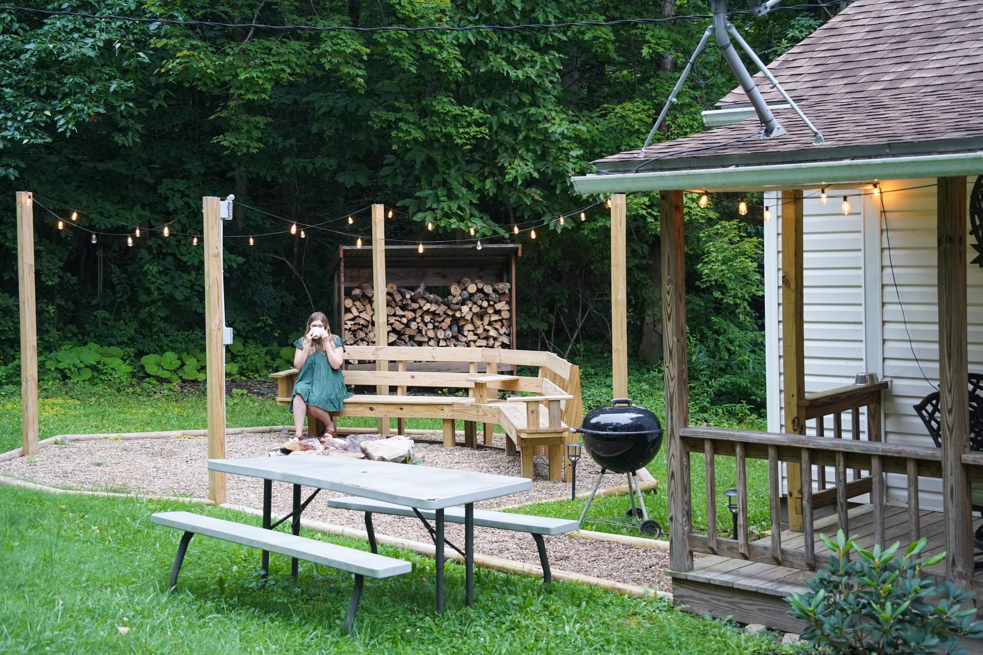 Lydia sitting on a wooden bench next to a fire place at the Ohiopyle Hideaway.