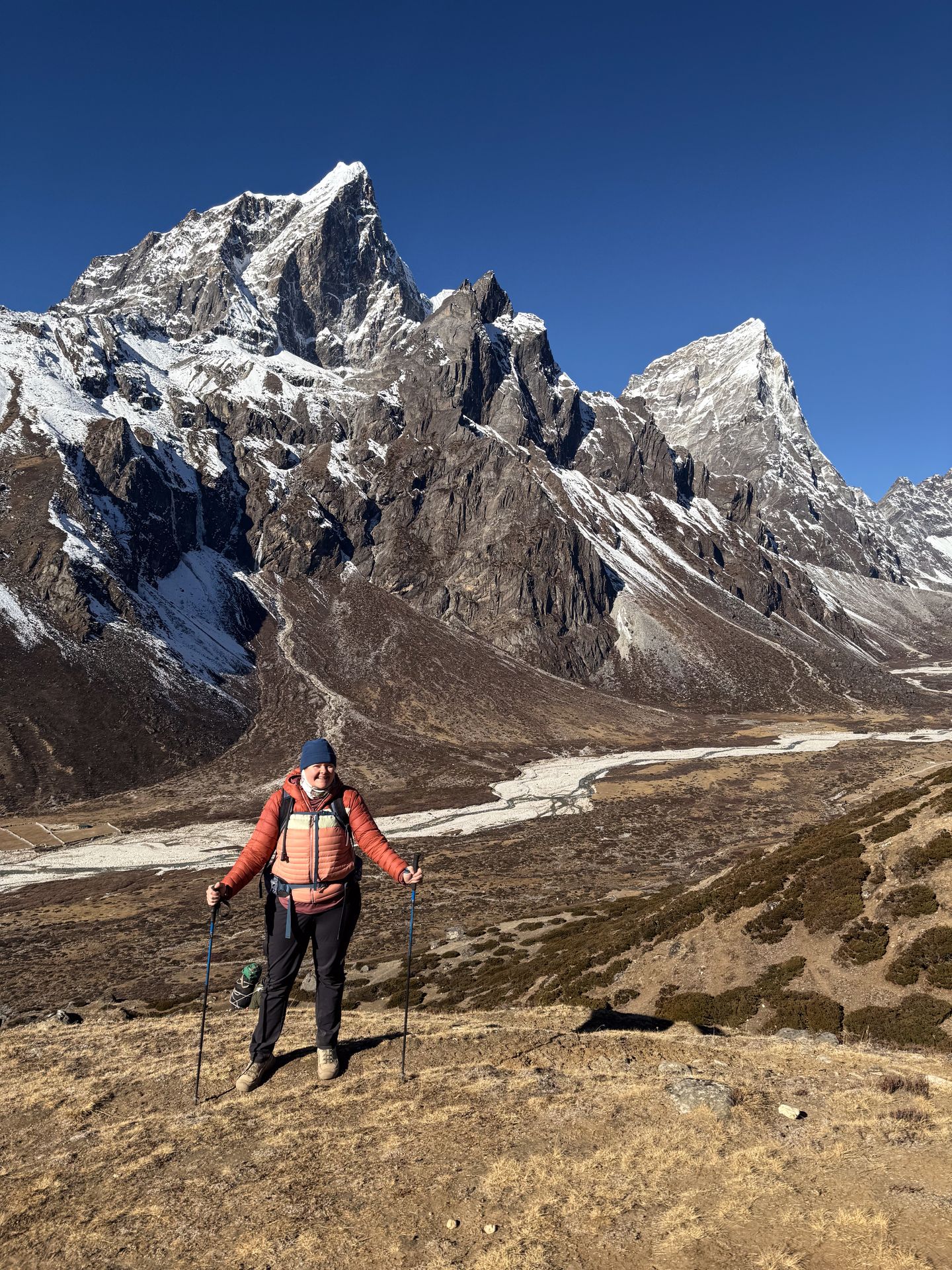 Lydia standing in front of a mountain scene while wearing a Cotopaxi jacket on the Everest Base Camp Trek