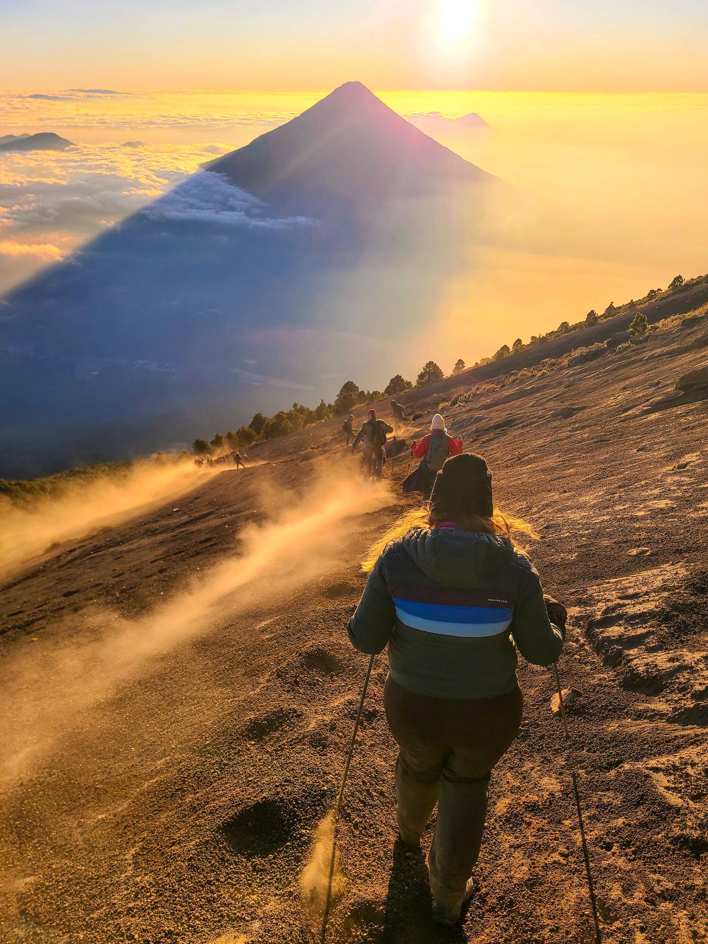 Lydia and a line of people hiking down a dusty area of Acatenango after sunrise