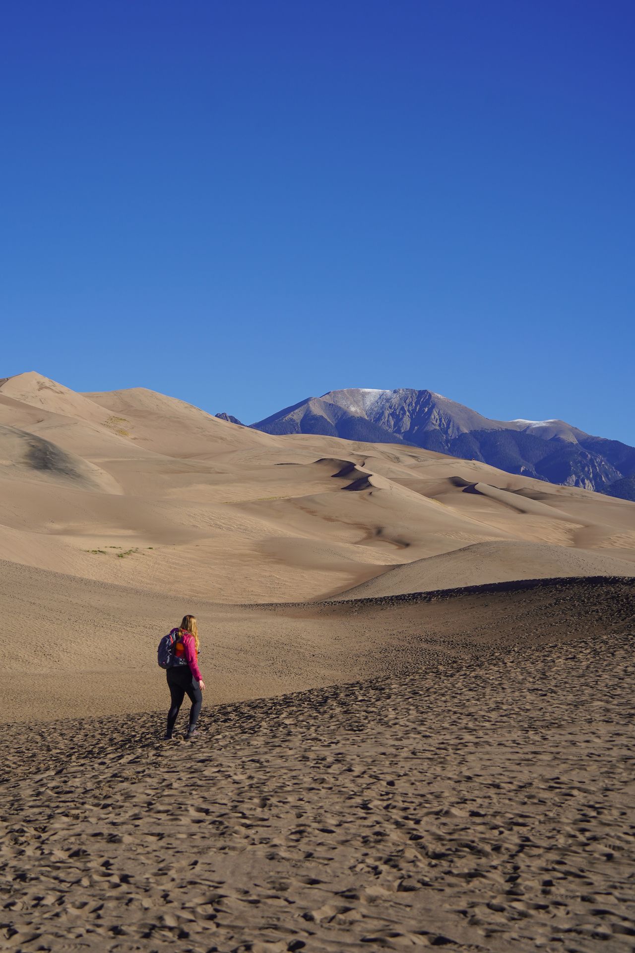 Lydia hiking among sand dunes with mountains in the distance