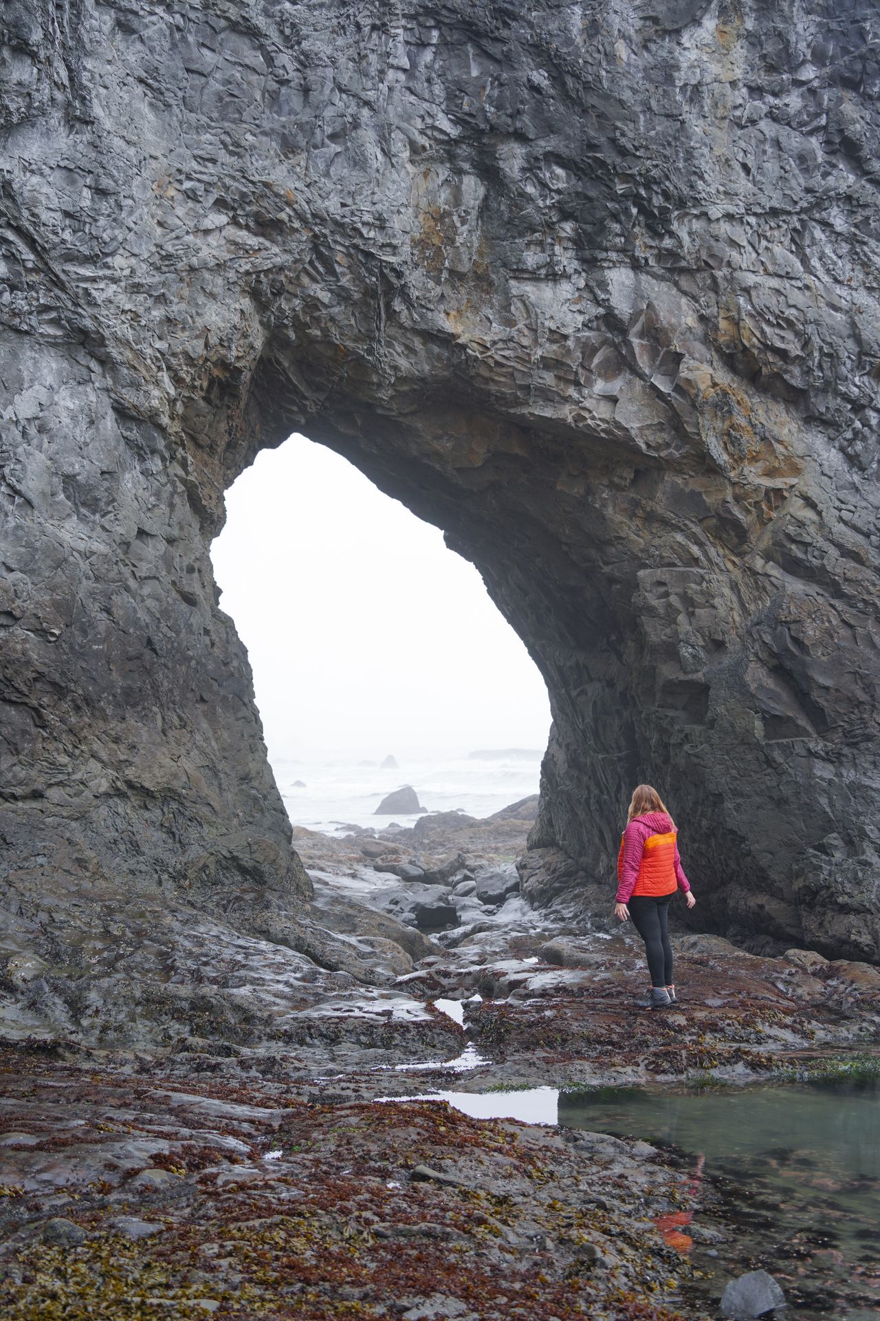 Lydia standing next to the Hole-in-the-Wall on Rialto Beach, which is an arch formation