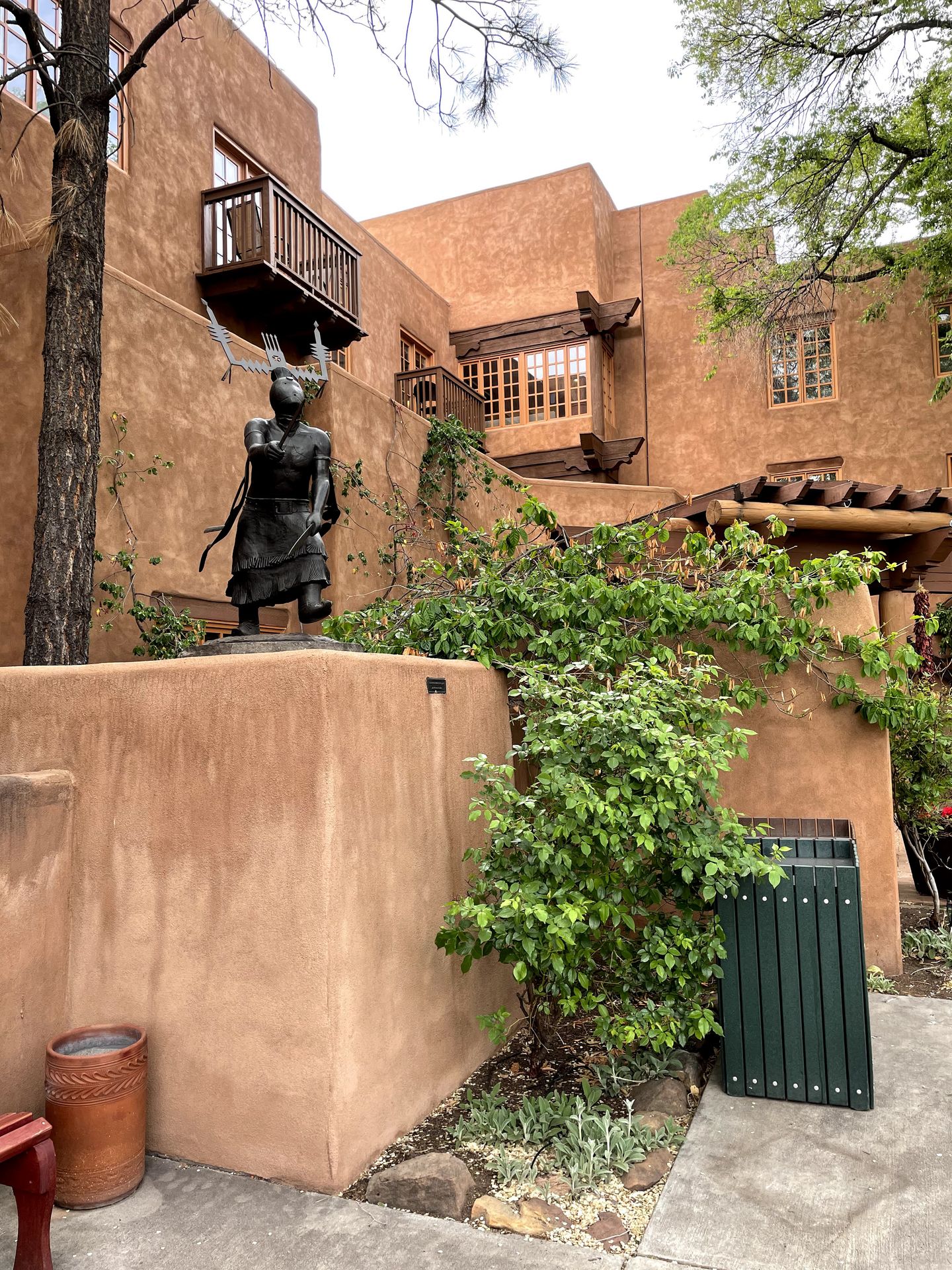 The Pueblo exterior of Hotel Santa Fe. There is a statue mixed in with the landscaping.