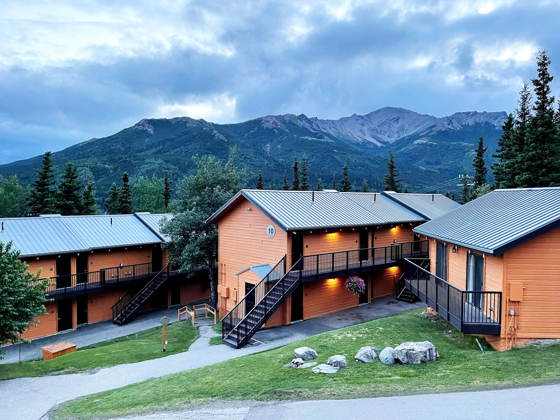 3 buildings part of the Denali Bluffs Hotel with mountains in the distance.