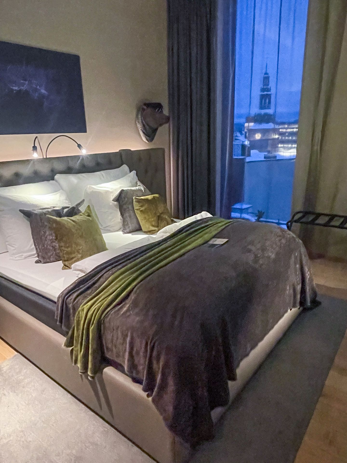 A hotel room in Clarion Hotel The Hub. There is a large bed and a view of a clock tower out the window.