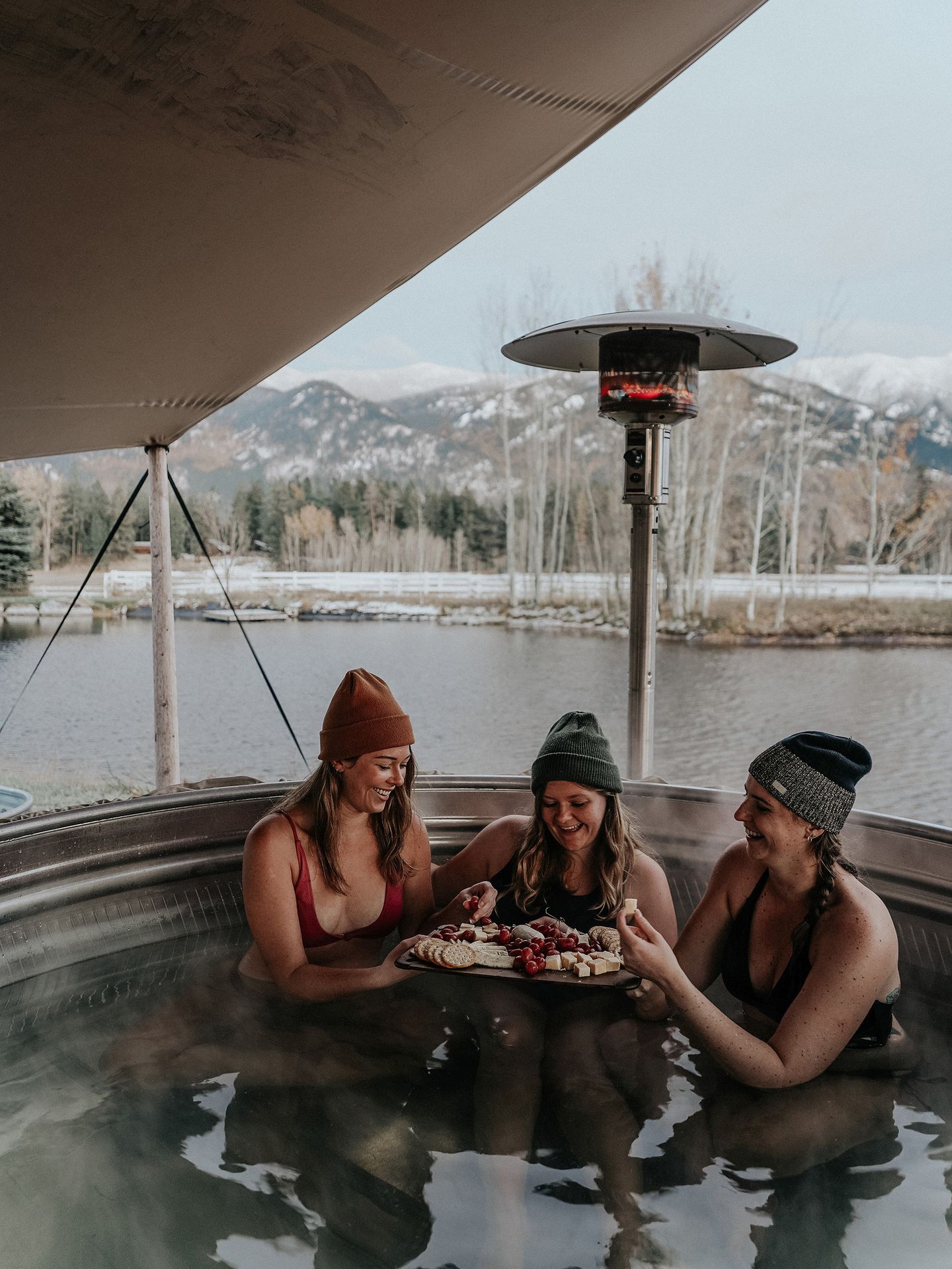 Lydia and two friends enjoying a charcuterie board inside a hot tub at ROAM Beyond