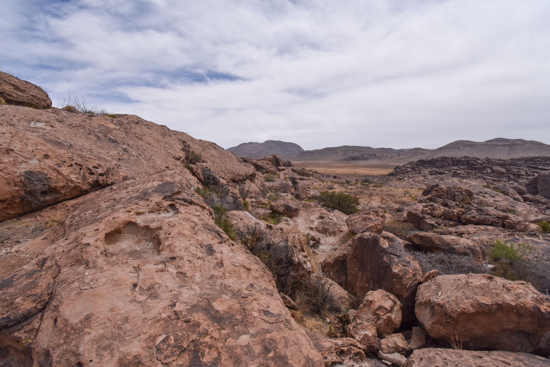 Standing up on top of rocks and looking at a landscape with tan rocks and boulders