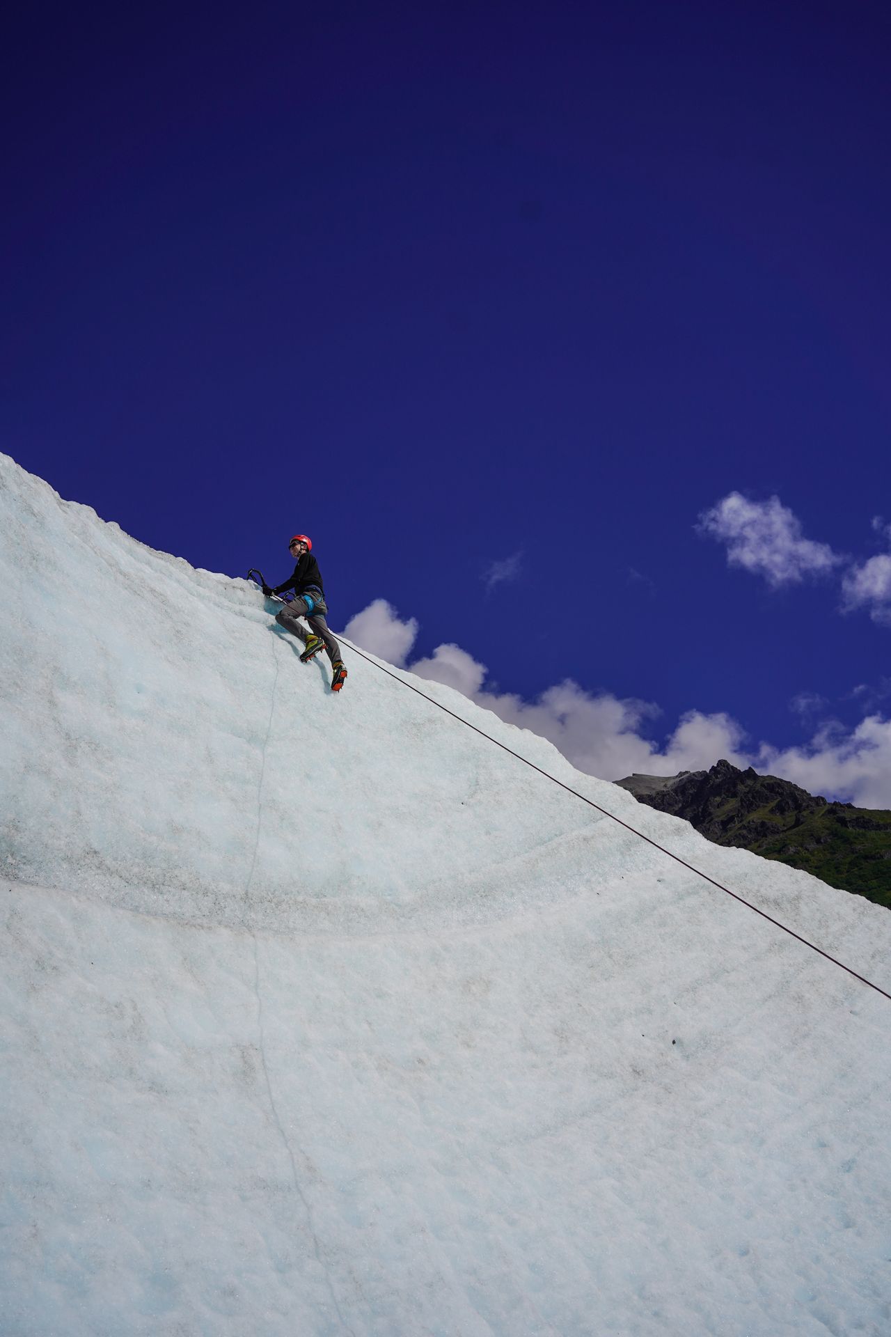 Joe at the top of an icy cliff while ice climbing in Wrangell-St. Elias