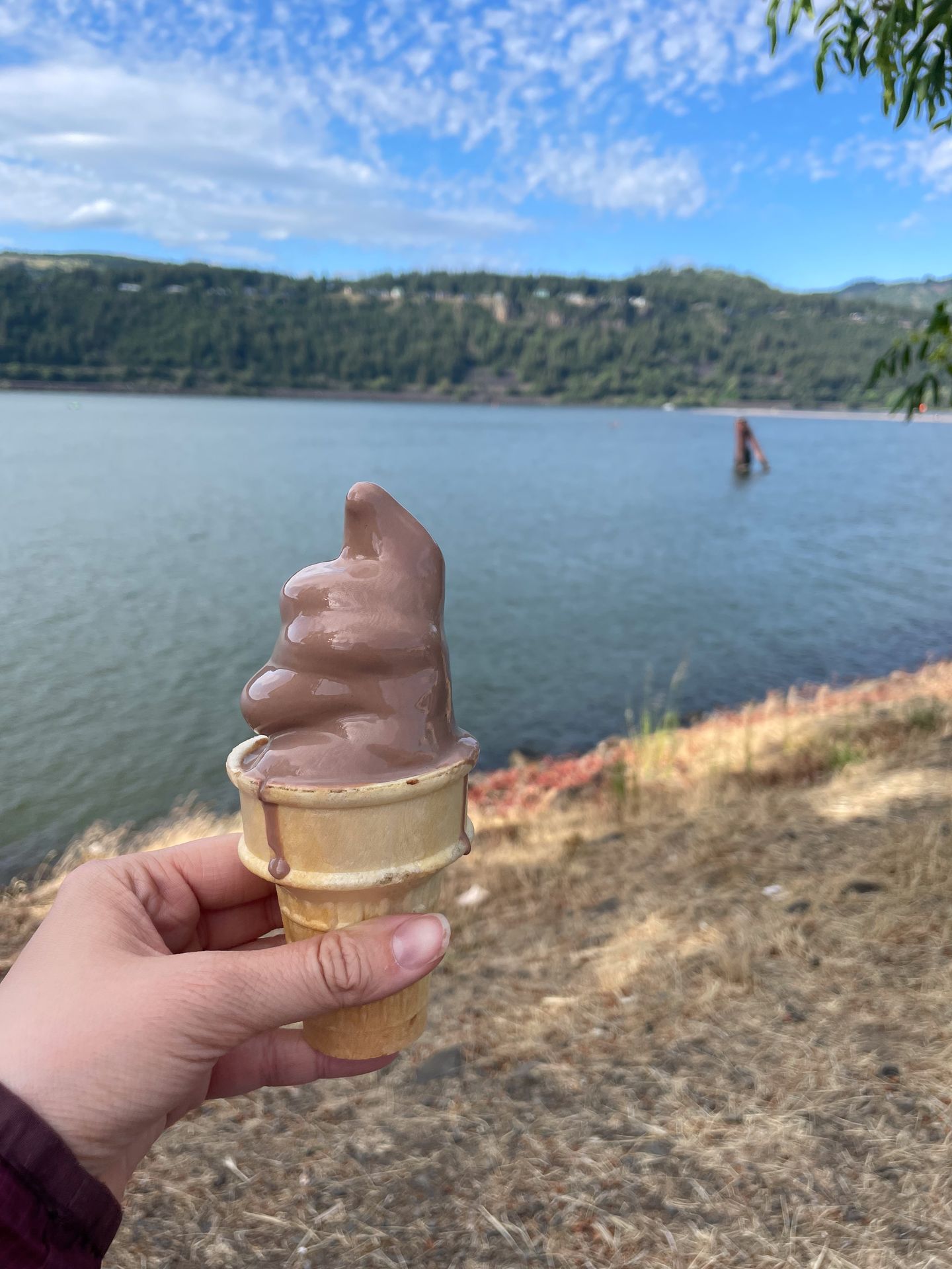 Holding up a cone with chocolate ice cream in front of the Columbia River in downtown Hood River
