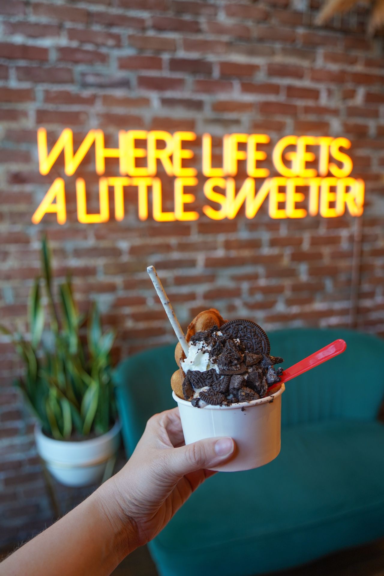Holding up an ice cream cup topped with oreos inside of House of Glory