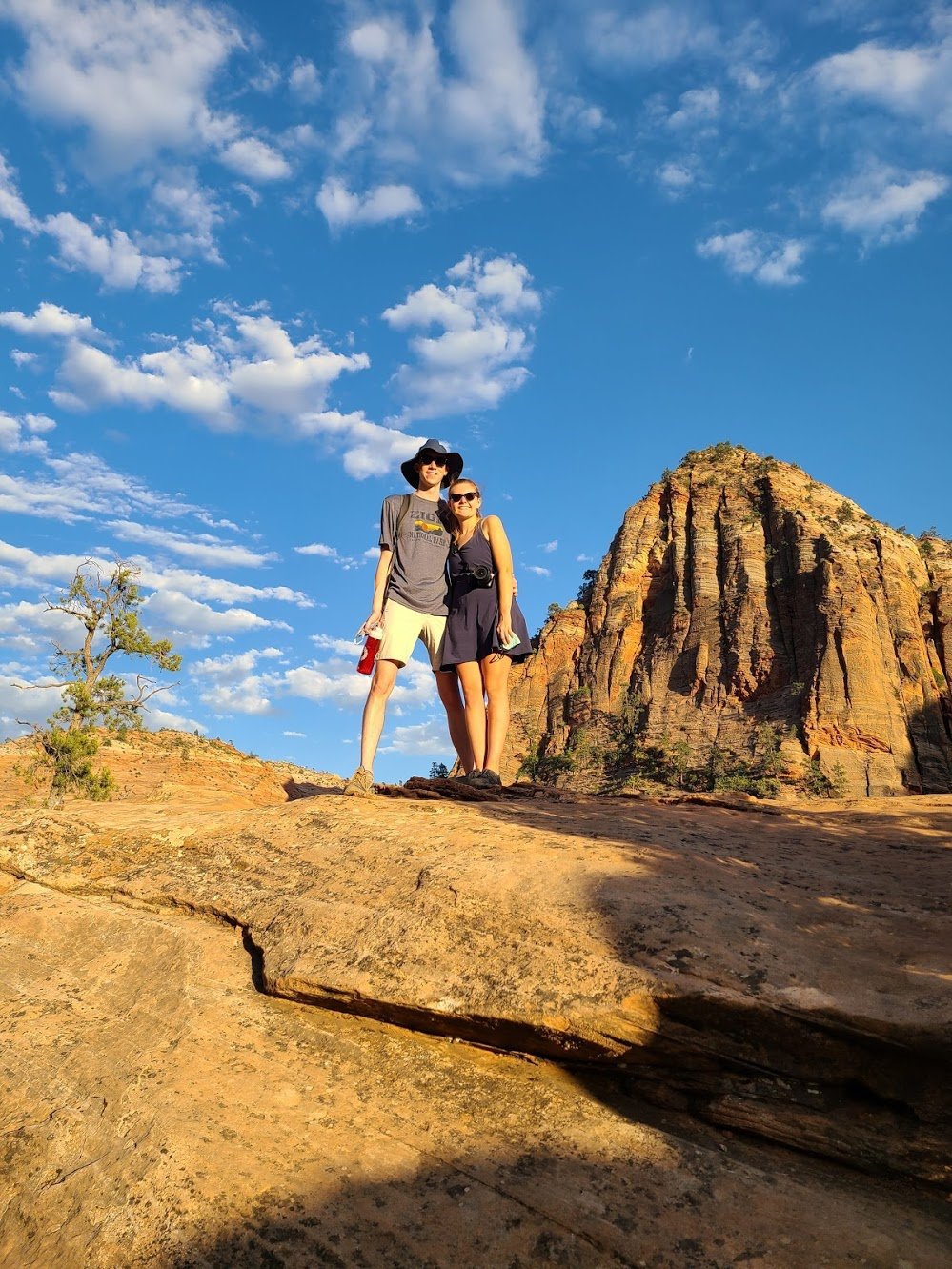 Lydia and Joe with an orange cliff behind them on the Canyon Overlook trail