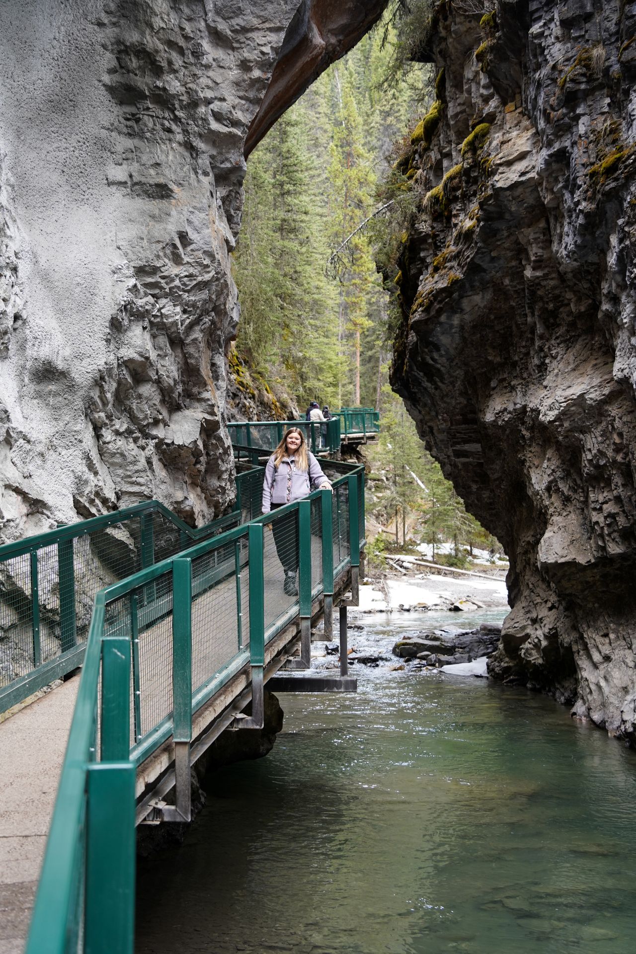 Lydia standing on a path that been build against the cliffs of a narrow canyon.