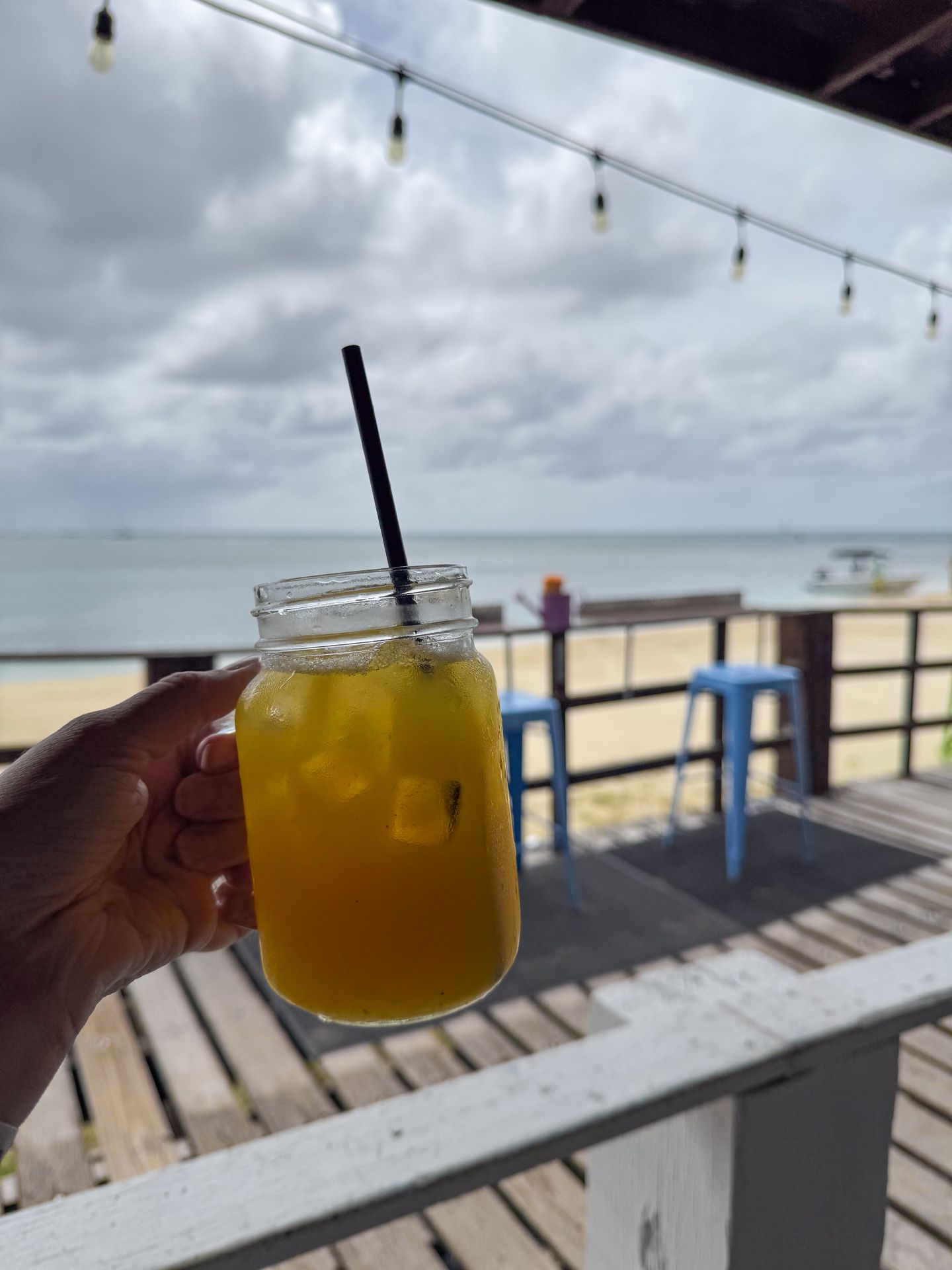 A bar full of passion fruit juice held up next to the ocean