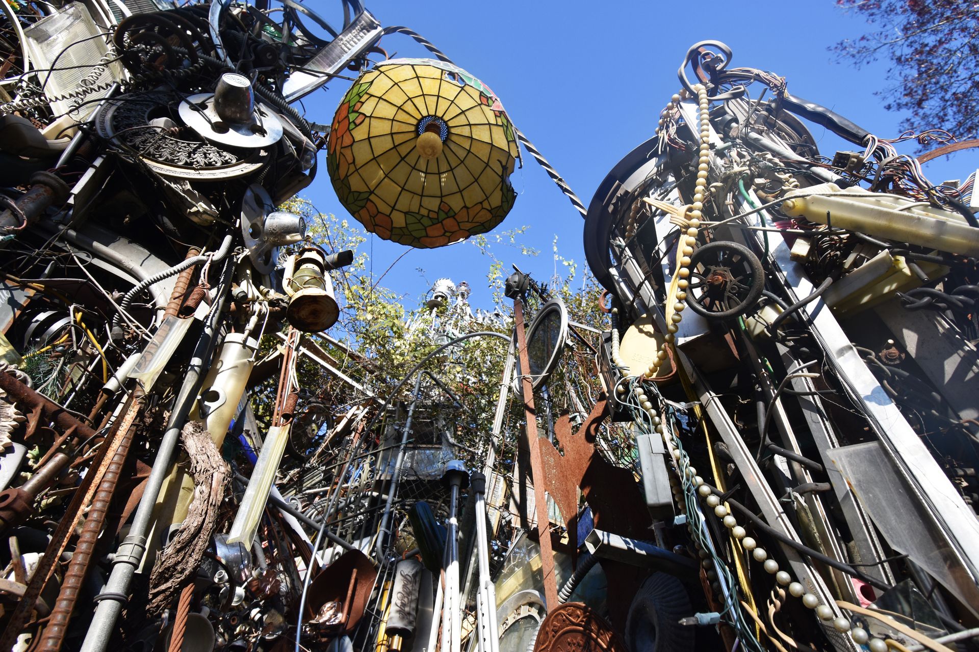 Looking up at the Cathedral of Junk, there is a stained glass lampshade, wheels and all sorts of other metals and materials to make up a structure.